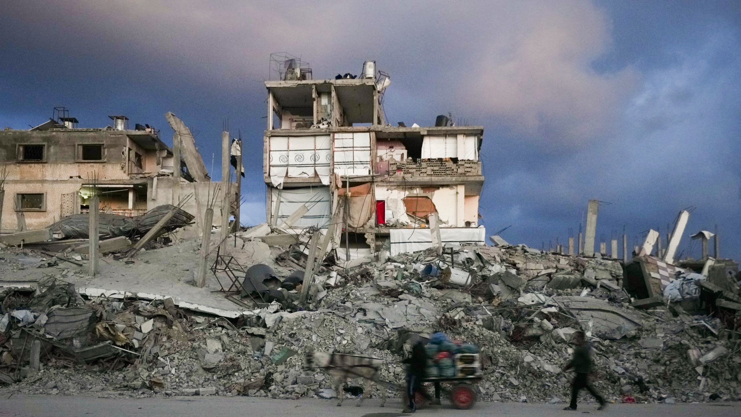 A man pushes a cart past a house that remains partly standing, but with sheets serving as makeshift walls, in an area largely destroyed by the Israeli army's air and ground offensive in Gaza City, Gaza Strip, Wednesday, Feb. 5, 2025. (AP Photo/Abdel Kareem Hana)