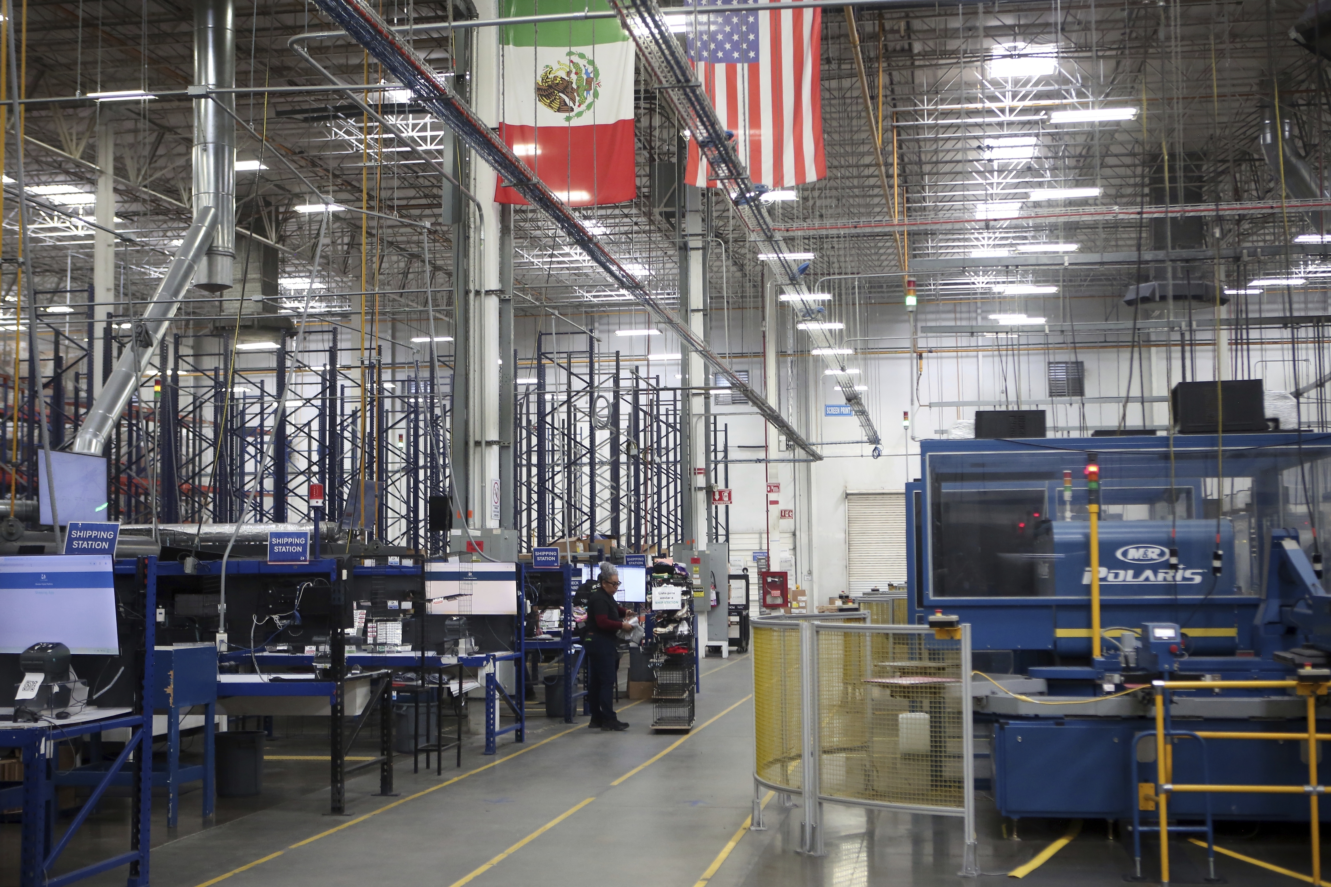 National flags representing the United States and Mexico hang inside in a textile factory that produces T-shirts, in Ciudad Juarez, Mexico, Tuesday, Feb. 4, 2025. (AP Photo/Christian Chavez)