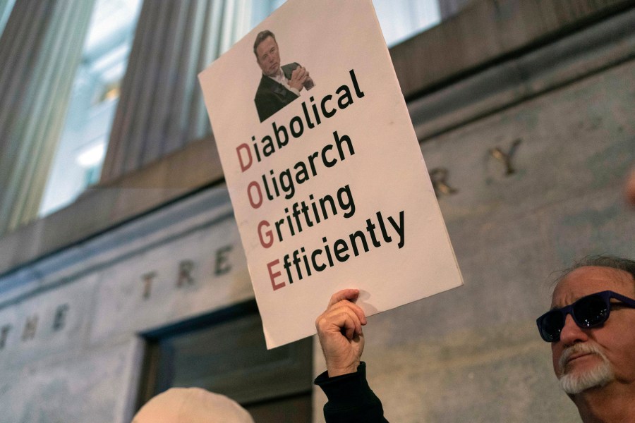 People protest during a rally against Elon Musk outside the Treasury Department in Washington, Tuesday, Feb. 4, 2025. (AP Photo/Jose Luis Magana)