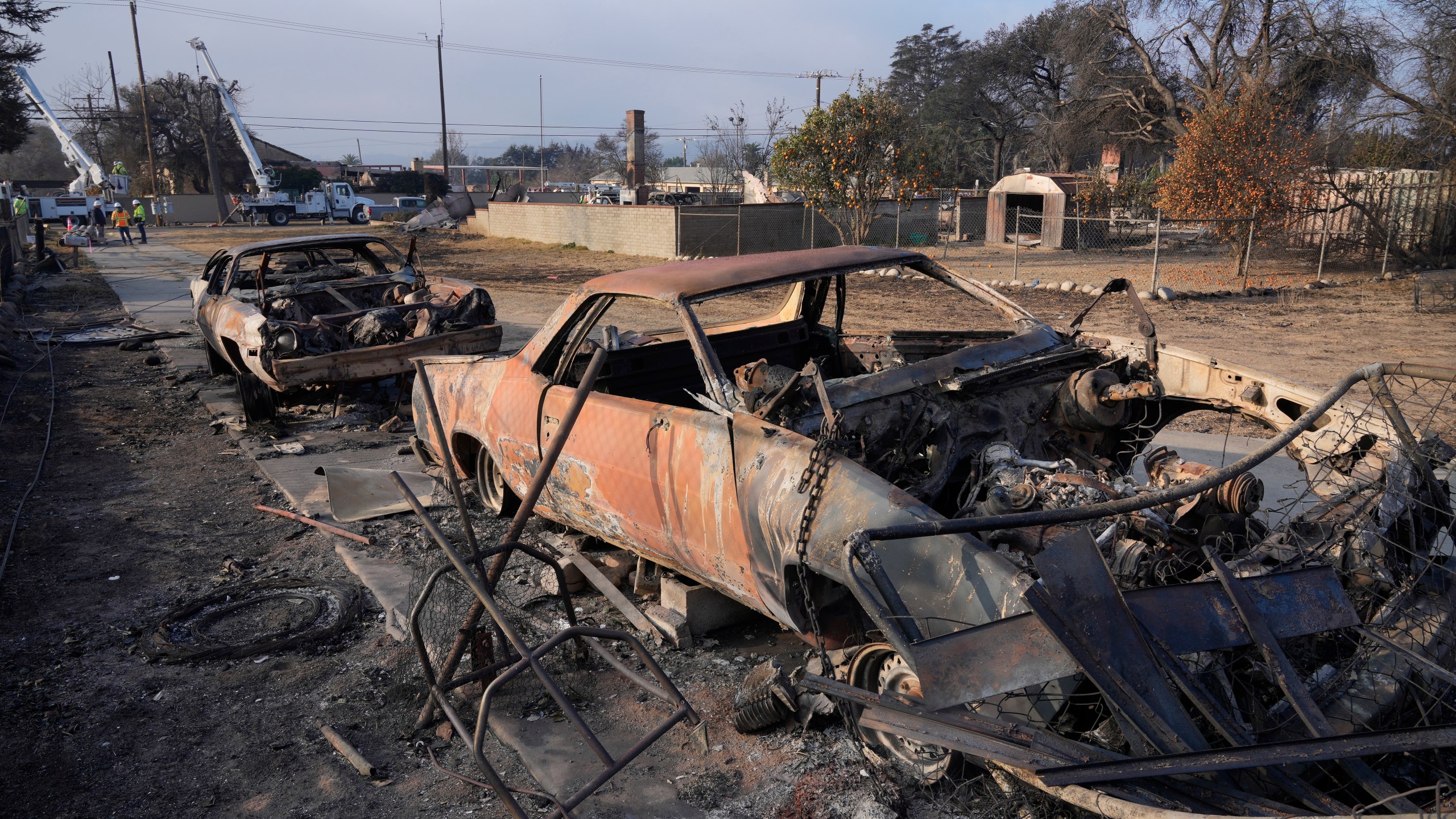 FILE - Southern California Edison utility company workers in rear try to restore power in the area destroyed by the Eaton Fire, Sunday, Jan. 19, 2025, in Altadena, Calif. (AP Photo/Damian Dovarganes, File)