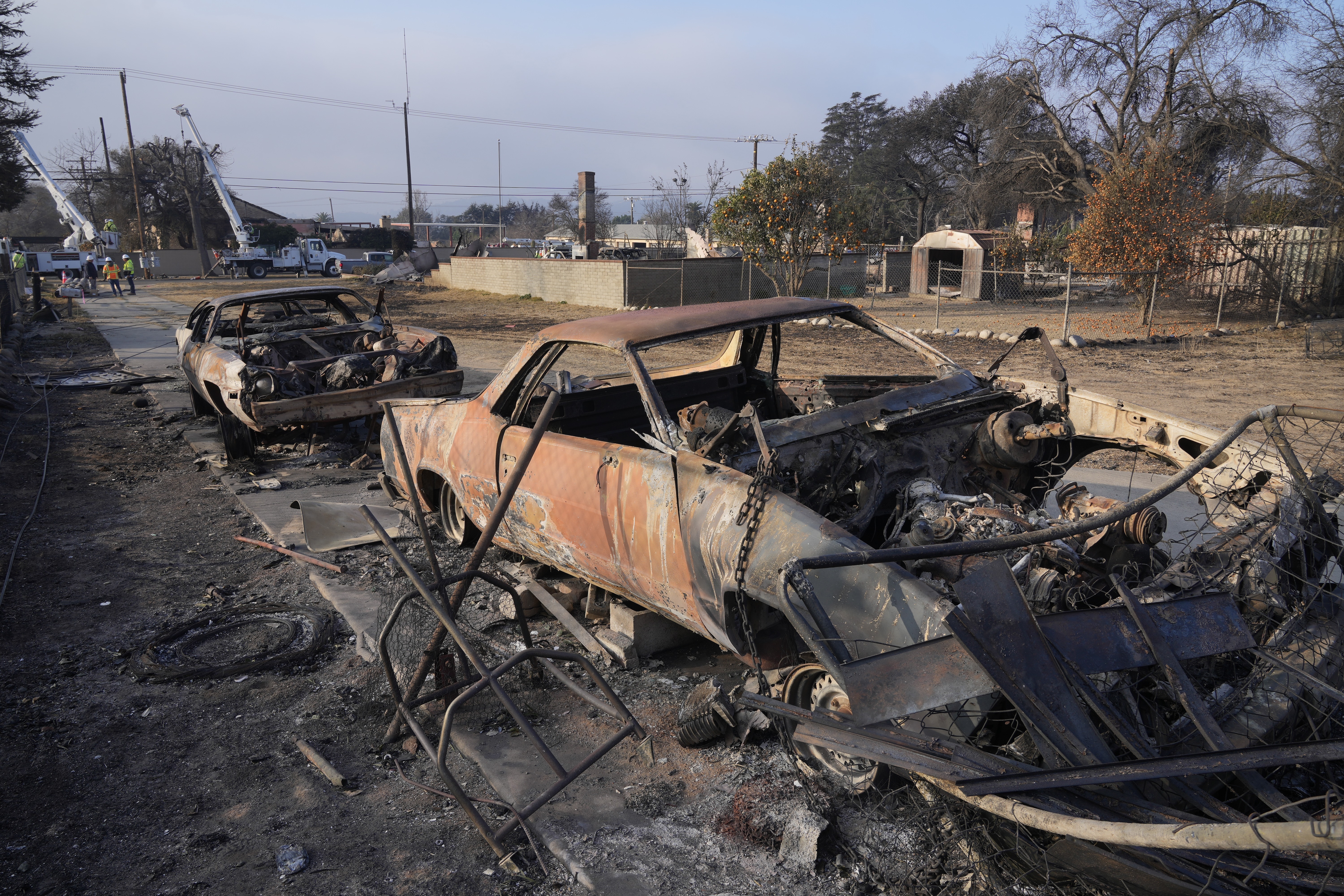 FILE - Southern California Edison utility company workers in rear try to restore power in the area destroyed by the Eaton Fire, Sunday, Jan. 19, 2025, in Altadena, Calif. (AP Photo/Damian Dovarganes, File)