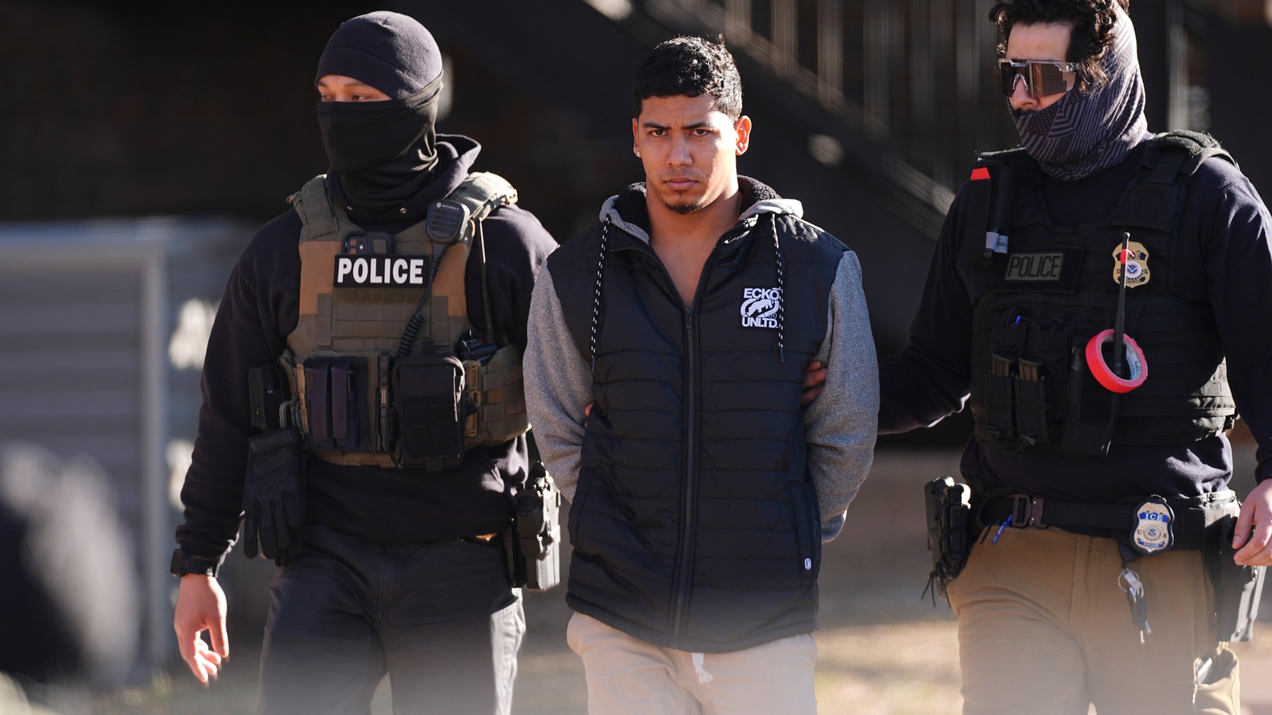 Law officials escort a suspect from an apartment to a waiting utility vehicle for transport during a raid Wednesday, Feb. 5, 2025, in east Denver. (AP Photo/David Zalubowski)