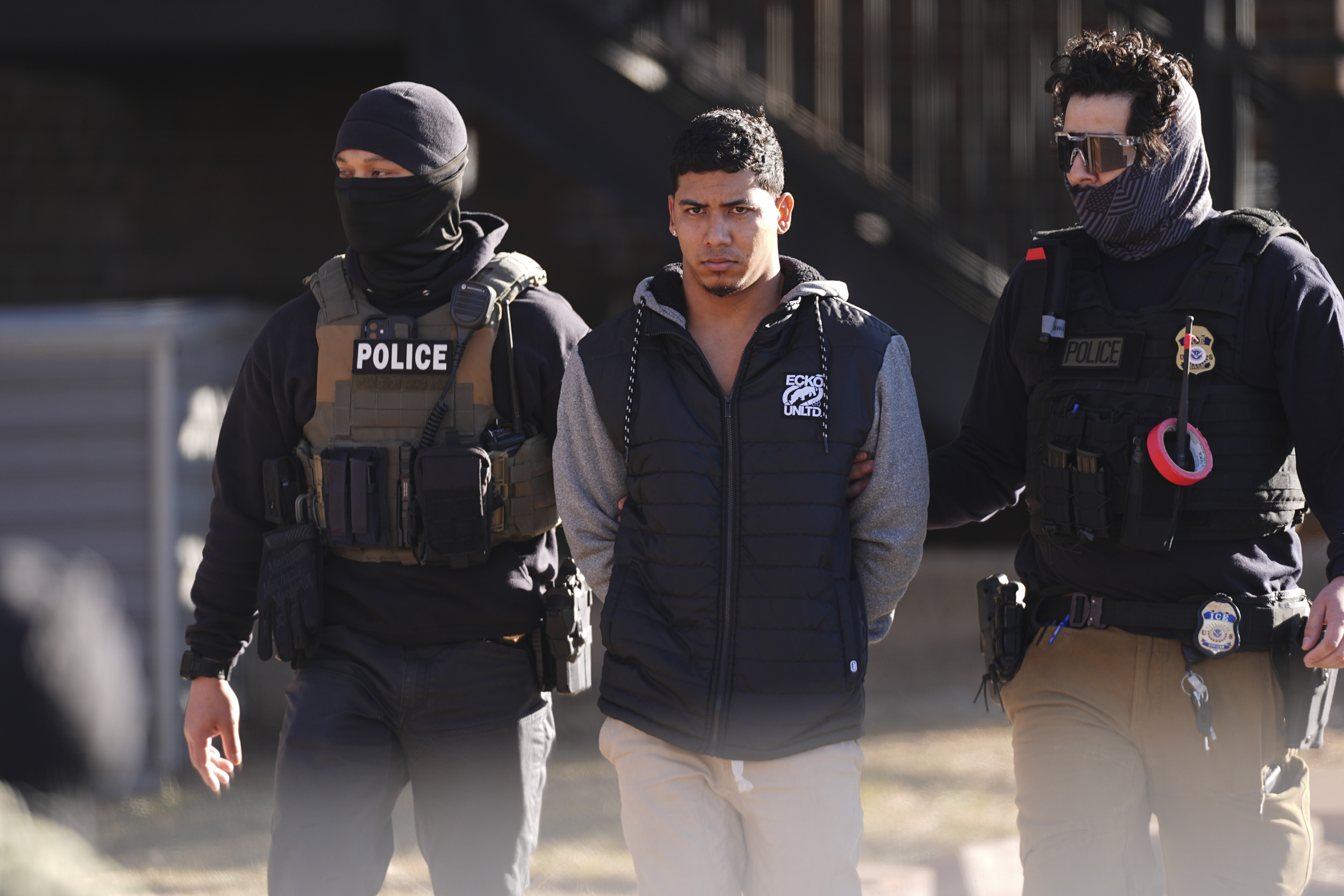 Law officials escort a suspect from an apartment to a waiting utility vehicle for transport during a raid Wednesday, Feb. 5, 2025, in east Denver. (AP Photo/David Zalubowski)