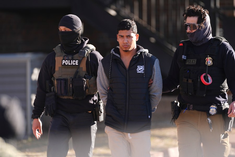 Law officials escort a suspect from an apartment to a waiting utility vehicle for transport during a raid Wednesday, Feb. 5, 2025, in east Denver. (AP Photo/David Zalubowski)