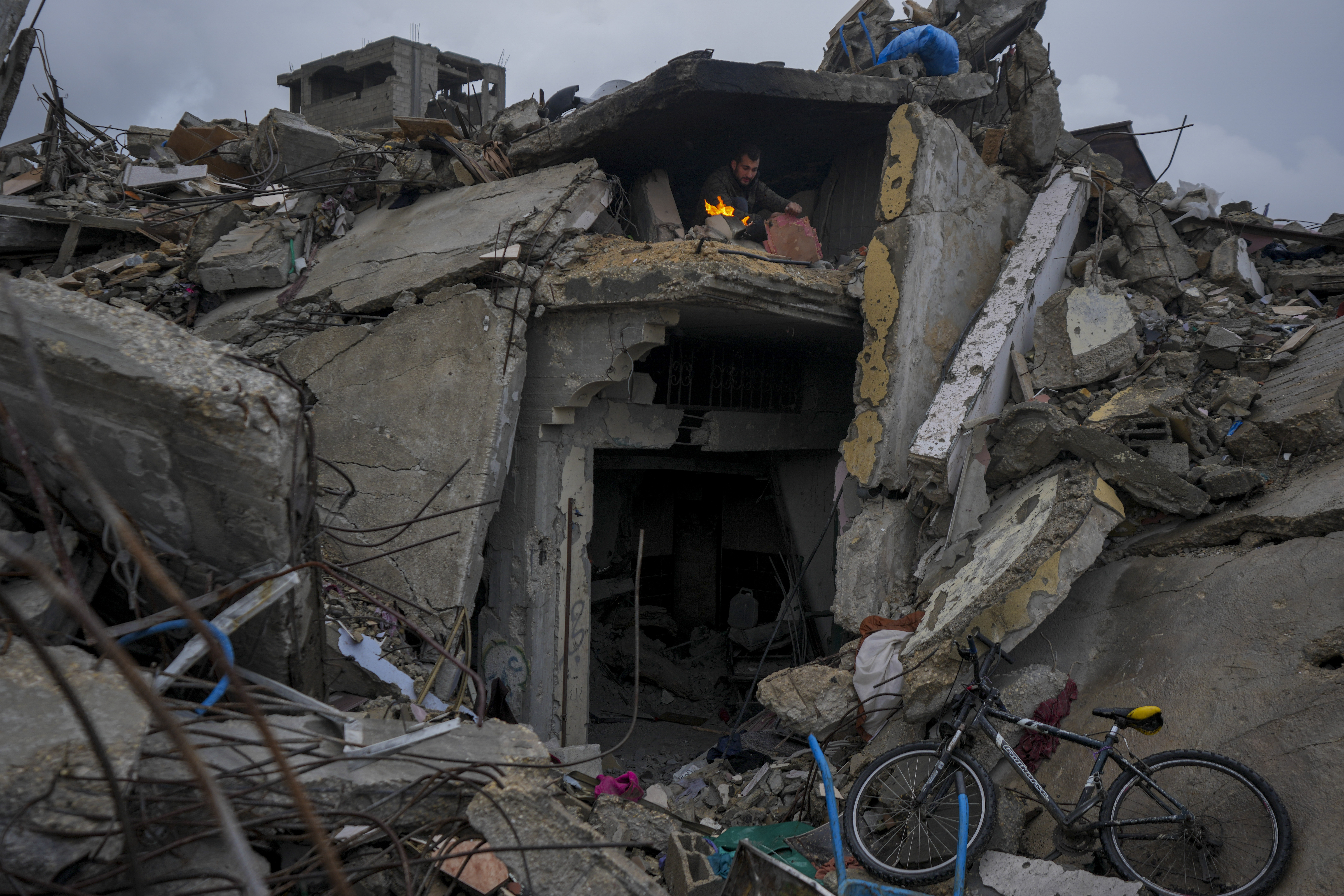 Mohammad Naser, sits by a fire as he takes cover from the rain under the destruction of his house caused by the Israeli air and ground offensive in Jabaliya, Gaza Strip, Thursday, Feb. 6, 2025. (AP Photo/Abdel Kareem Hana)