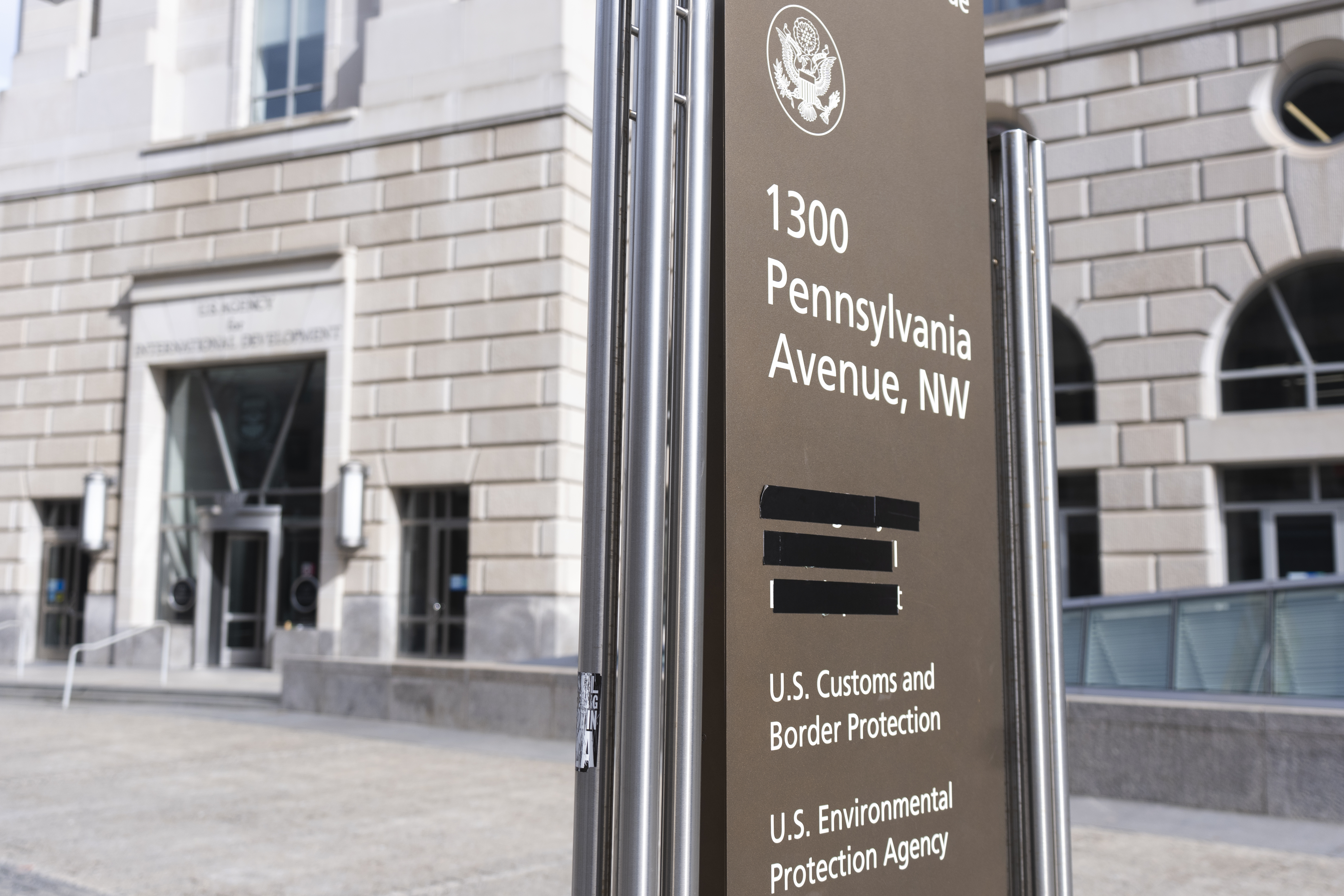 A street sign with names of U.S. government agencies housed at the Ronald Reagan Building, including the United States Agency for International Development, or USAID headquarters in Washington, is pictured with one building occupant taped, Friday, Feb. 7, 2025, in Washington. (AP Photo/Manuel Balce Ceneta)