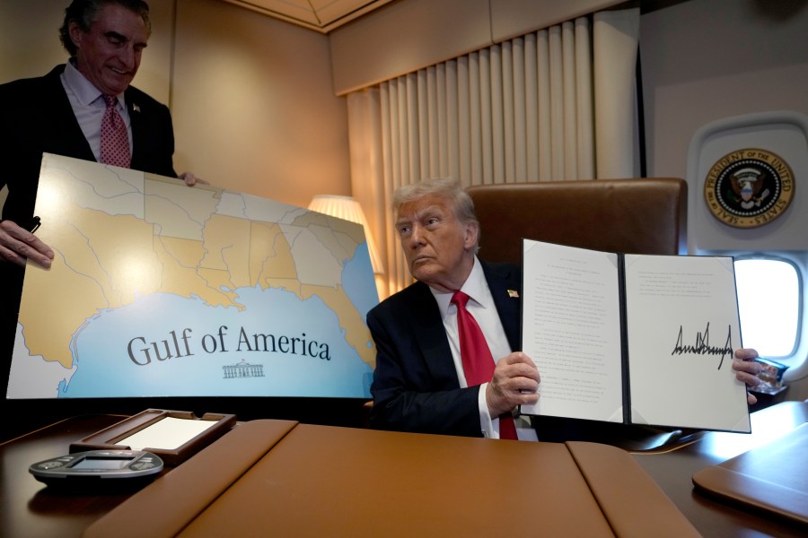 President Donald Trump holds up a signed proclamation declaring Feb. 9 Gulf of America Day, as Interior Secretary Doug Burgum watches aboard Air Force One as Trump travels from West Palm Beach, Fla. to New Orleans, Sunday, Feb. 9, 2025. (AP Photo/Ben Curtis)