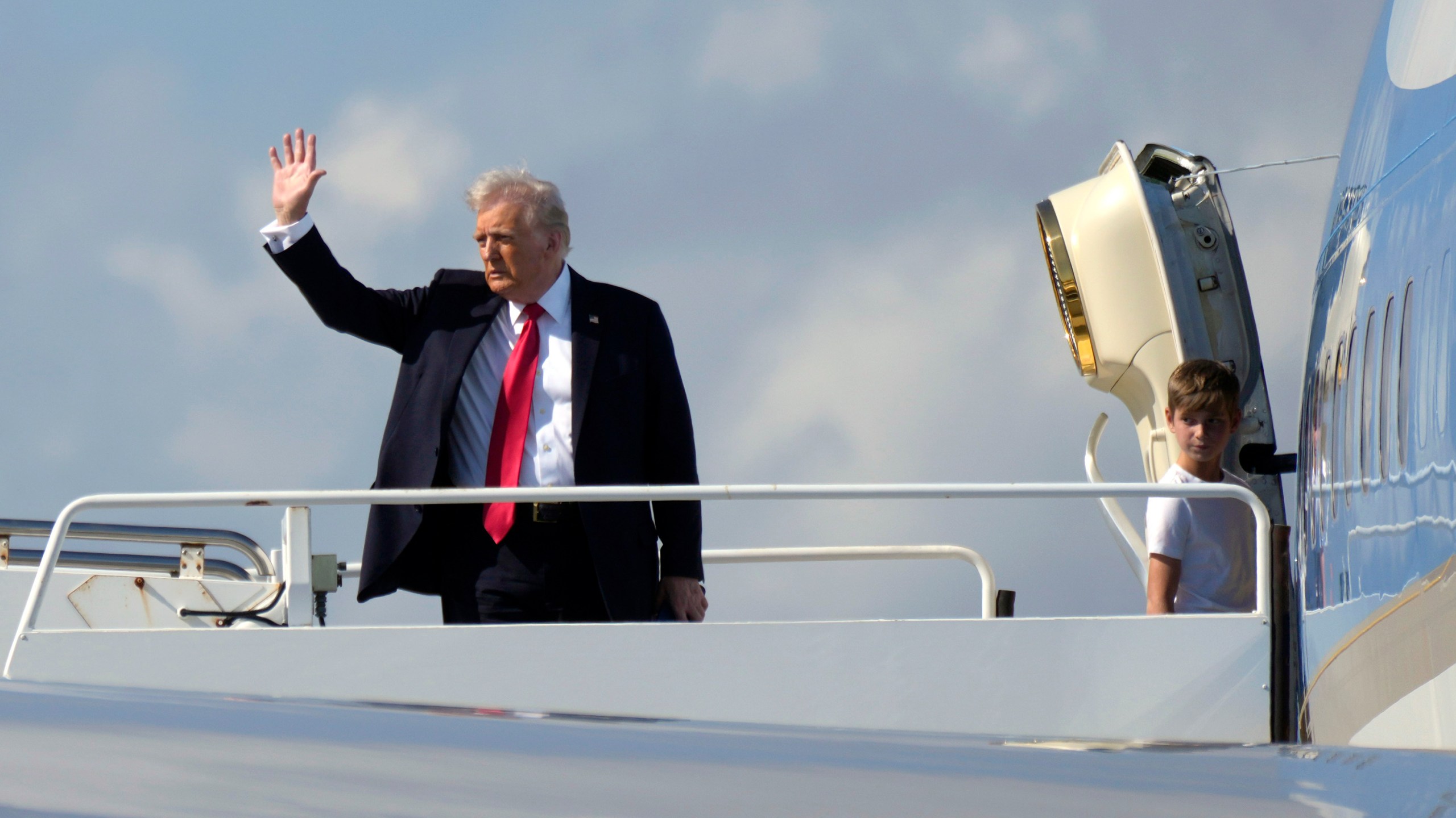 President Donald Trump, left, waves as he boards Air Force One with grandson Theodore, Ivanka Trump's son, at Palm Beach International Airport in West Palm Beach, Fla., Sunday, Feb. 9, 2025. (AP Photo/Ben Curtis)