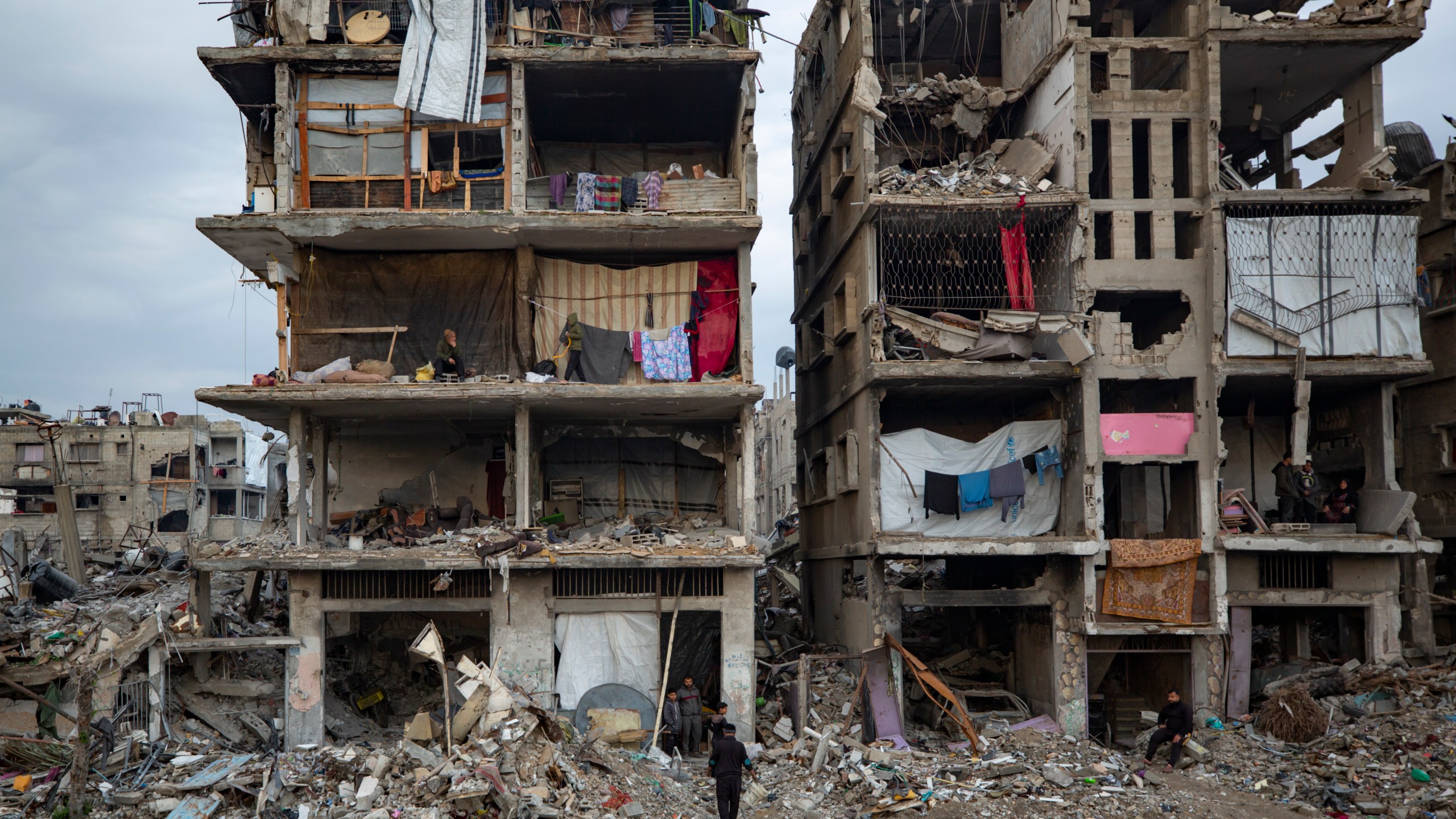 Palestinians sit in their partially standing homes, covered with sheets as makeshift walls, in an area largely destroyed by the Israeli army's air and ground offensive in Jabaliya, Gaza Strip, Tuesday, Feb. 11, 2025. (AP Photo/Jehad Alshrafi)