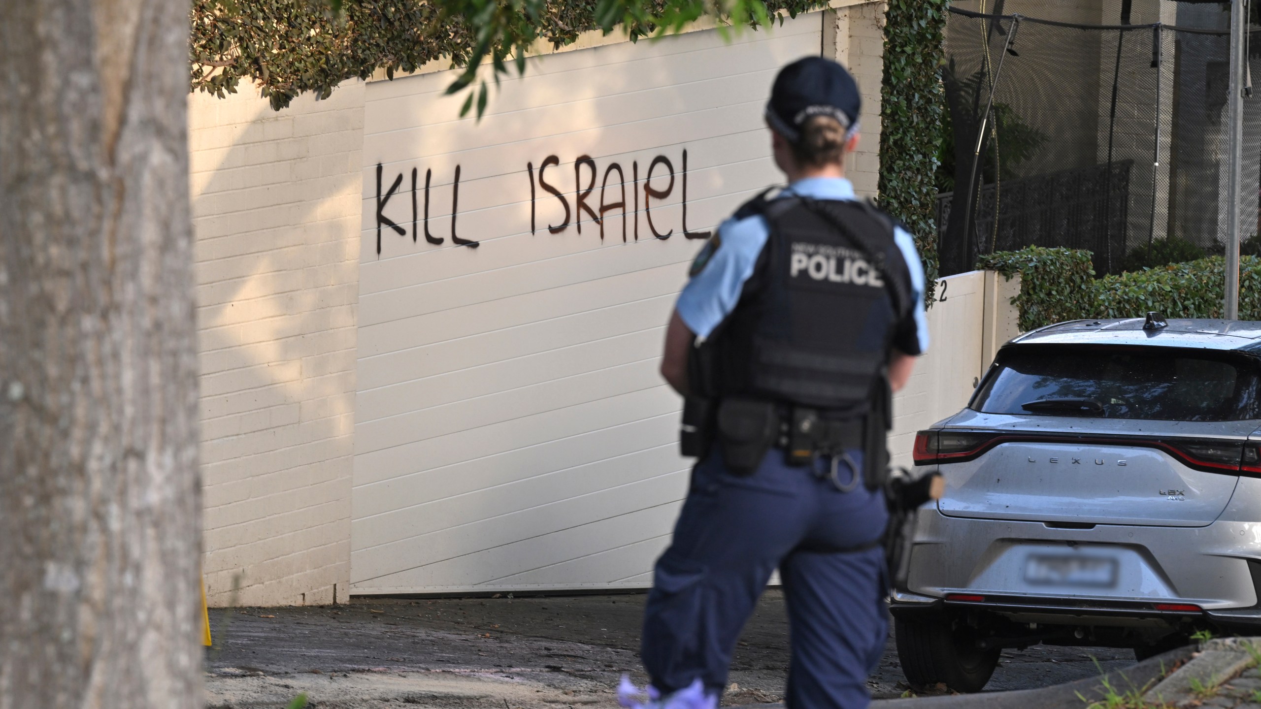 A police officer stands near where anti-Israel graffiti is painted on a wall in Sydney, Australia, on Dec. 11, 2024. (Mick Tsikas/AAP Image via AP)y