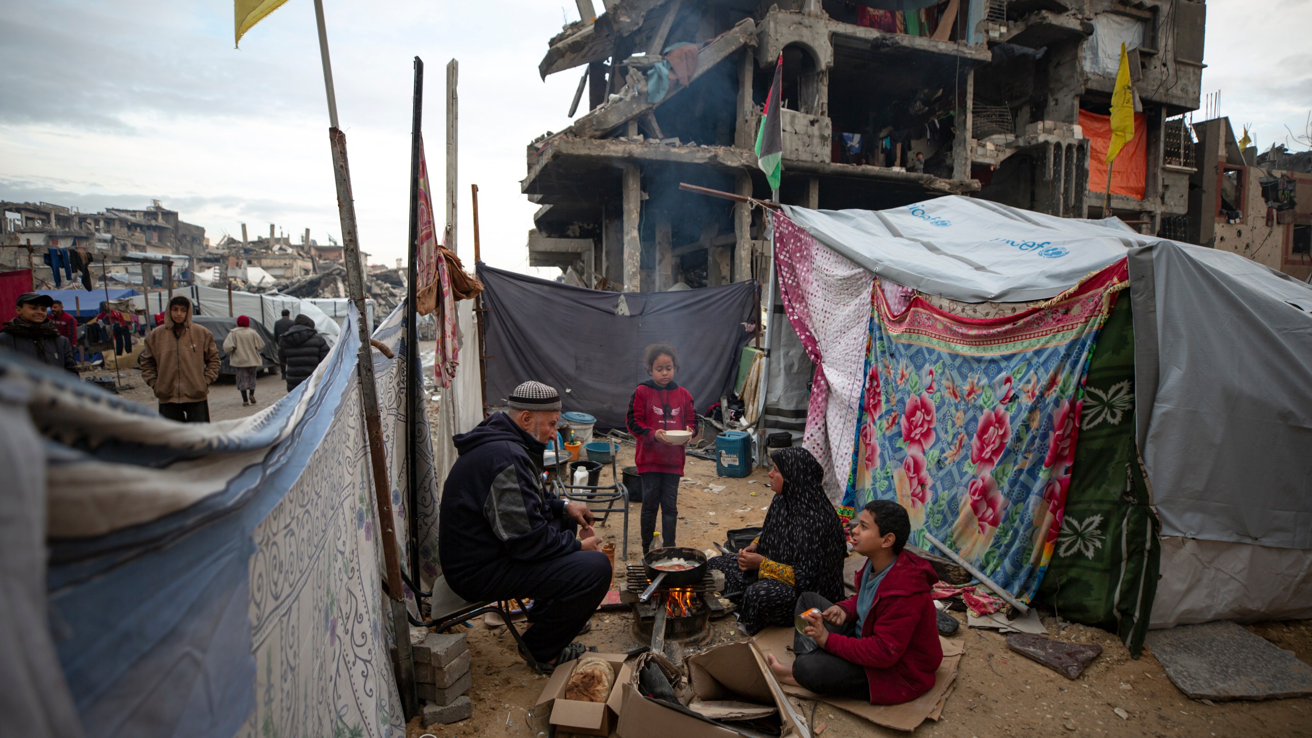 A Palestinian family cooks on fire next to their tent, in an area largely destroyed by the Israeli army's air and ground offensive in Jabaliya, Gaza Strip, on Tuesday, Feb. 11, 2025. (AP Photo/Jehad Alshrafi)