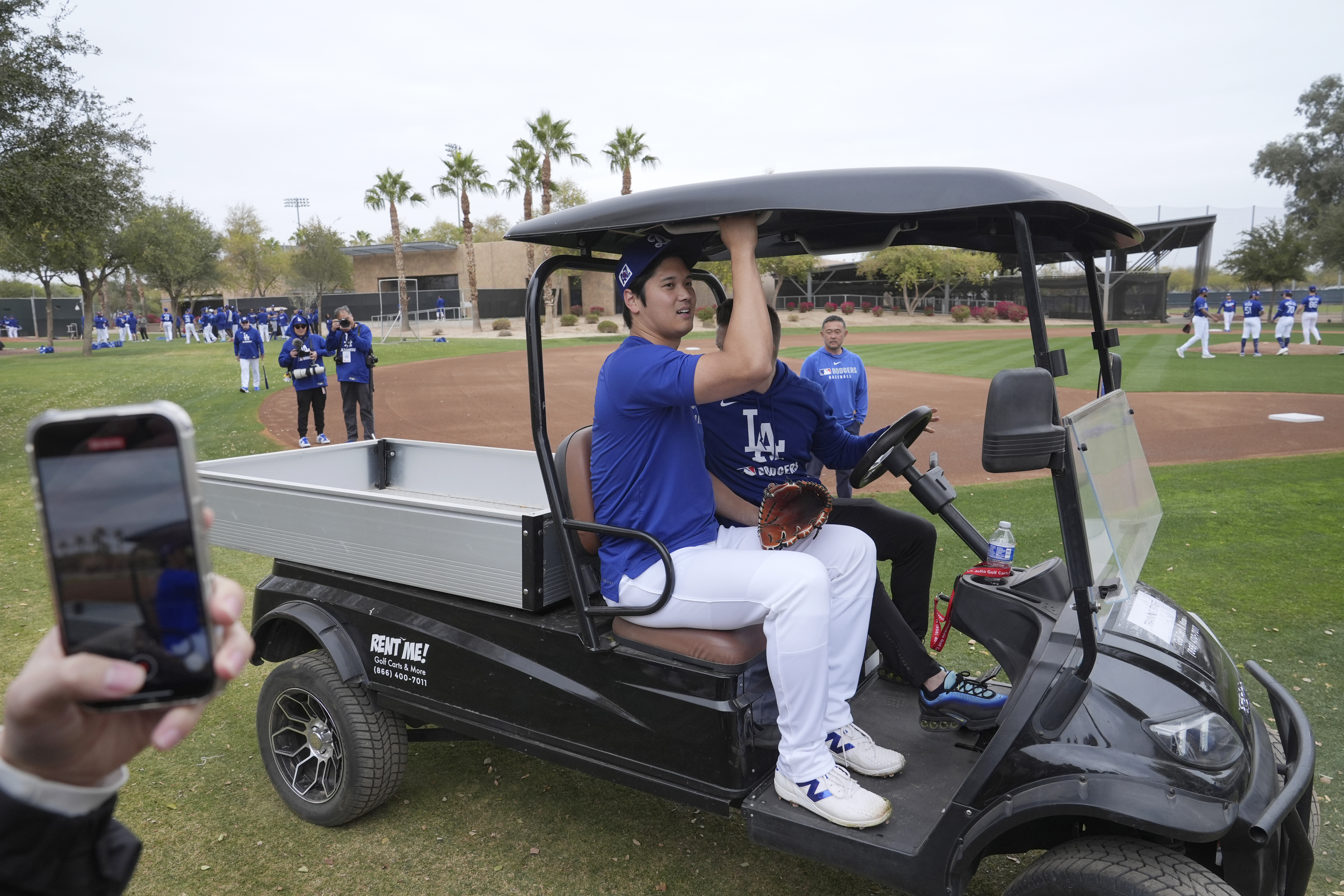 Los Angeles Dodgers' Shohei Ohtani, of Japan, gets a ride back to the clubhouse at the team's baseball spring training facility Wednesday, Feb. 12, 2025, in Phoenix. (AP Photo/Ross D. Franklin)