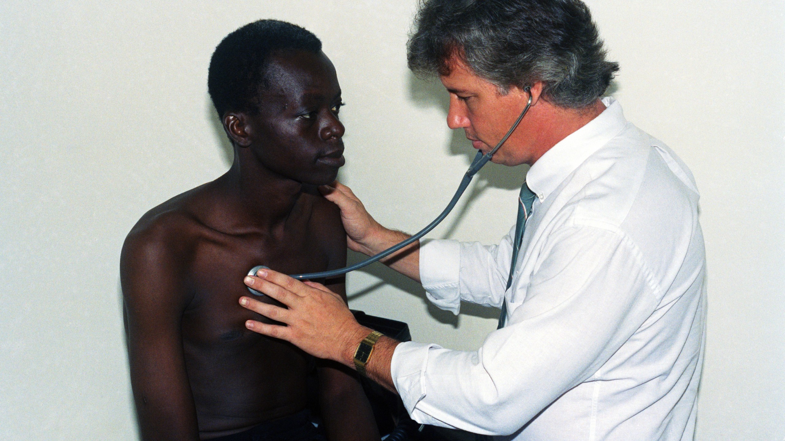 FILE - American doctor Mark Ottenweller, right, examines AIDS patient Yacouba Guengane in his clinic in Abidjan, Ivory Coast, Nov. 18, 1991. (AP Photo, File)