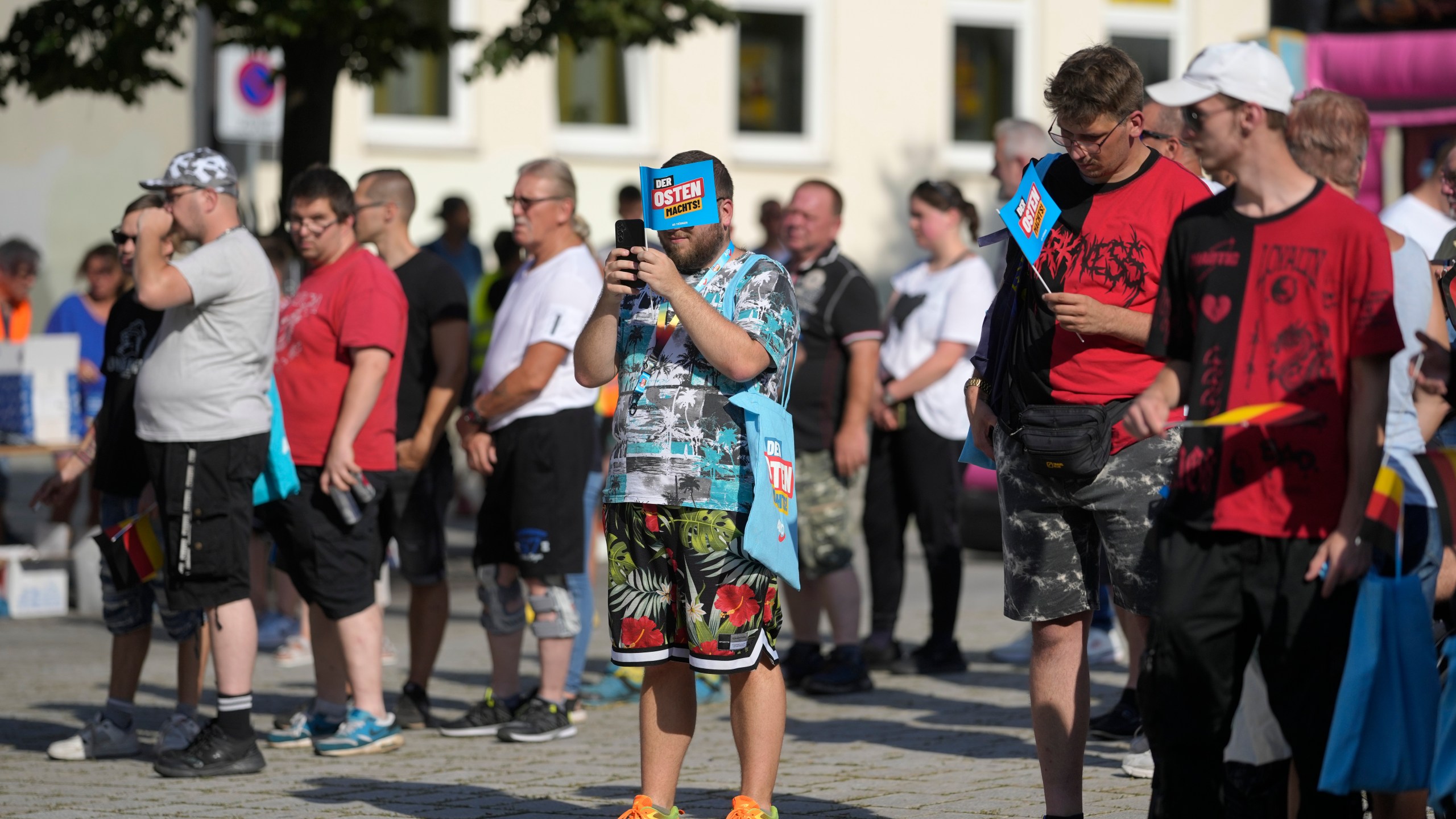 FILE - Supporters of the far-right Alternative for Germany party, or AfD, hold small paper flags that read: "The East Does it", as they attend an election campaign rally of the party for upcoming state elections in Suhl, Germany, Aug. 13, 2024. (AP Photo/Markus Schreiber, File)