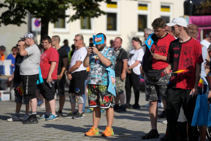 FILE - Supporters of the far-right Alternative for Germany party, or AfD, hold small paper flags that read: "The East Does it", as they attend an election campaign rally of the party for upcoming state elections in Suhl, Germany, Aug. 13, 2024. (AP Photo/Markus Schreiber, File)