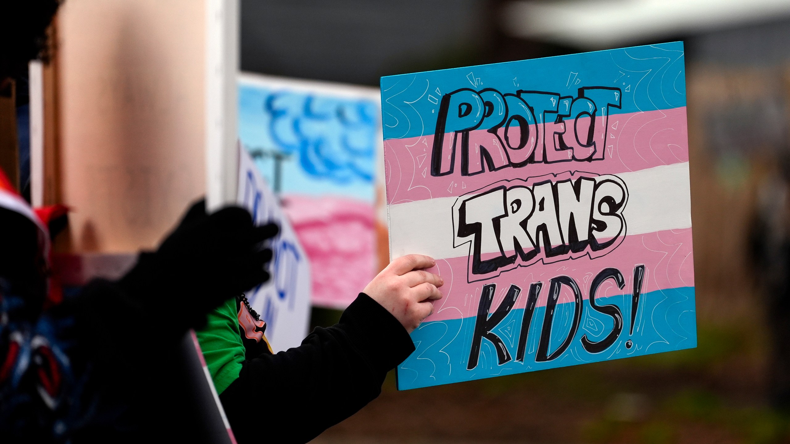 FILE - A person holds a sign during a pro-transgender rights protest outside of Seattle Children's Hospital after the institution postponed some gender-affirming surgeries for minors following an executive order by President Donald Trump, Sunday, Feb. 9, 2025, in Seattle. (AP Photo/Lindsey Wasson, File)