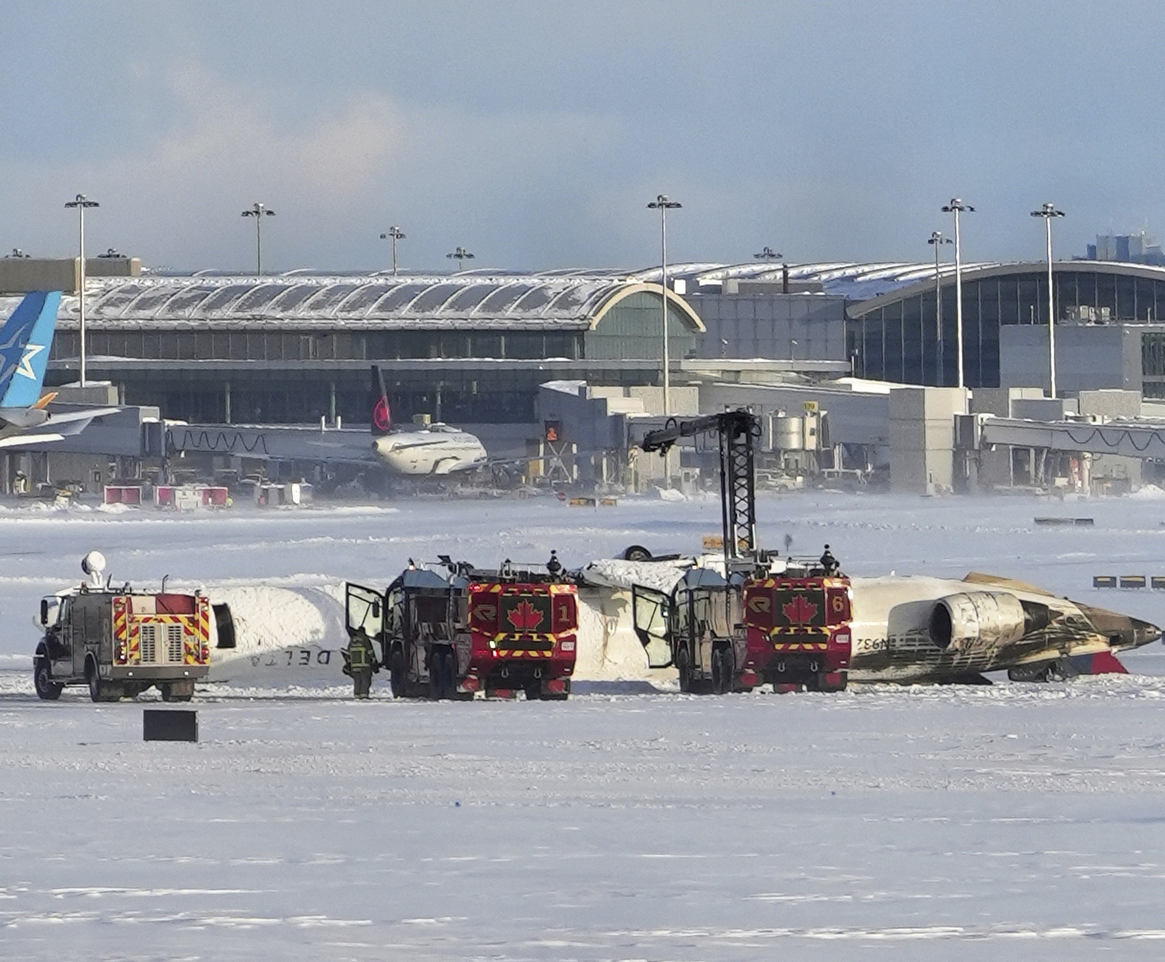 An aircraft from Delta Airlines sits upside down on the tarmac at Toronto Pearson International airport, Monday, Feb. 17, 2025. (Teresa Barbieri/The Canadian Press via AP)