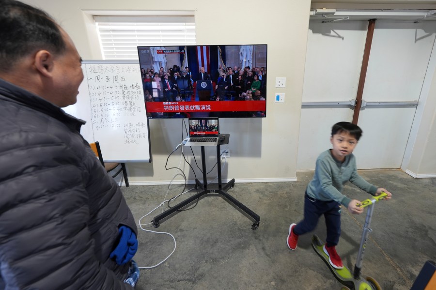 Pastor Pan Yongguang, left, part of a group of Chinese Christians resettled in Texas and awaiting final approval of their refugee status, watches a Chinese-captioned live broadcast of President Donald Trump's inauguration, Monday, Jan. 20, 2025, in Midland, Texas. (AP Photo/Rebecca Blackwell)