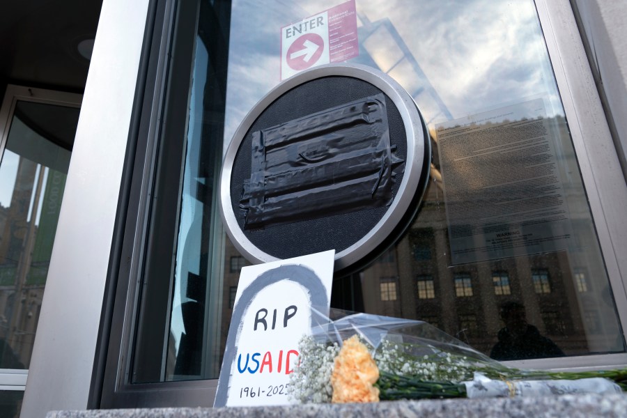 Flowers and a sign are placed outside the headquarters of the U.S. Agency for International Development, or USAID, Friday, Feb. 7, 2025, in Washington. (AP Photo/Jose Luis Magana)