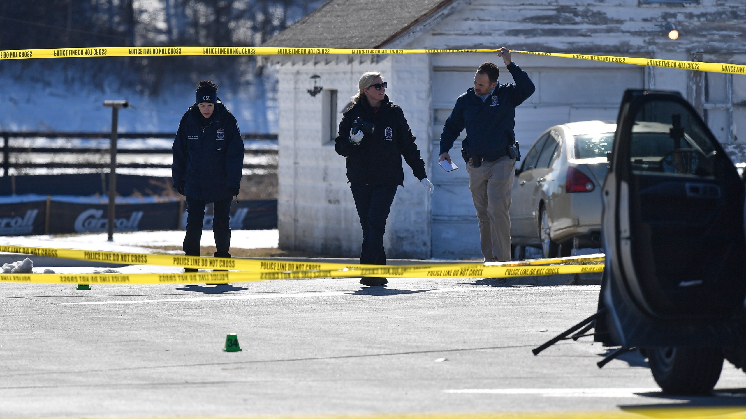 Detectives with the Louisville Metro Crime Scene unit examines a scene of a deadly shooting outside a motor vehicle office in Louisville, Ky., Friday, Feb. 21, 2025. (AP Photo/Timothy D. Easley)