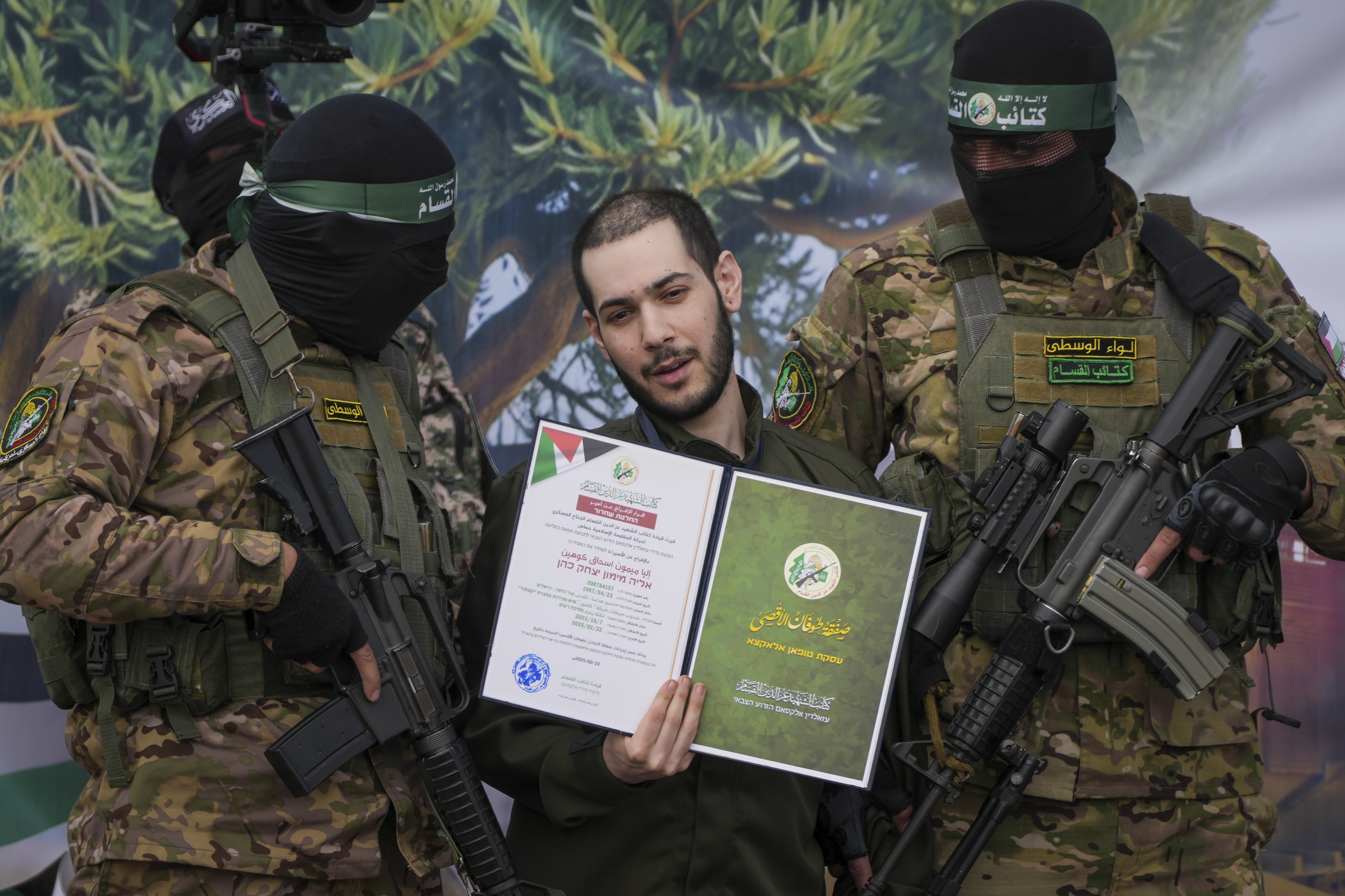 Israeli hostage Eliya Cohen, centre, is instructed to show a Hamas issued certificate while being escorted by militants to be handed over to the Red Cross in Nuseirat, central Gaza Strip, Saturday, Feb. 22, 2025. (AP Photo/Abdel Kareem Hana)