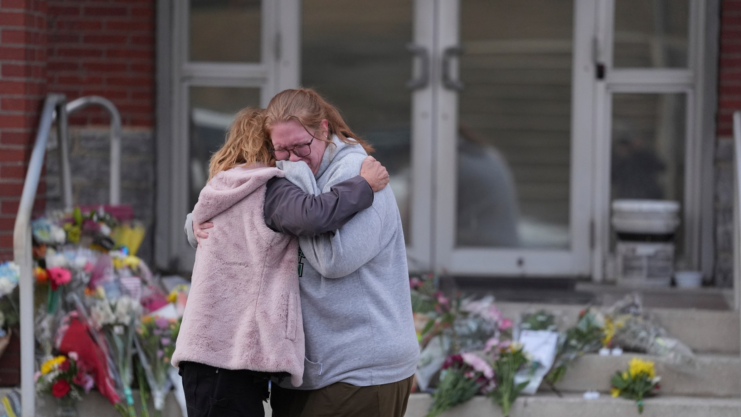 Leah Fauth gets a hug after leaving flowers in front of the West York Police Department after a police officer was killed responding to a shooting at UPMC Memorial Hospital in York, Pa. on Saturday, Feb. 22, 2025. (AP Photo/Matt Rourke)