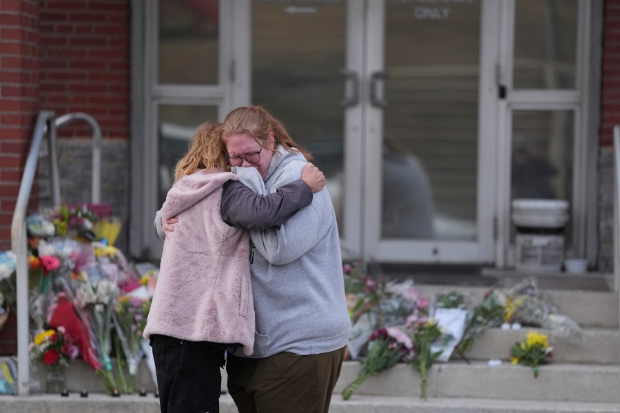 Leah Fauth gets a hug after leaving flowers in front of the West York Police Department after a police officer was killed responding to a shooting at UPMC Memorial Hospital in York, Pa. on Saturday, Feb. 22, 2025. (AP Photo/Matt Rourke)