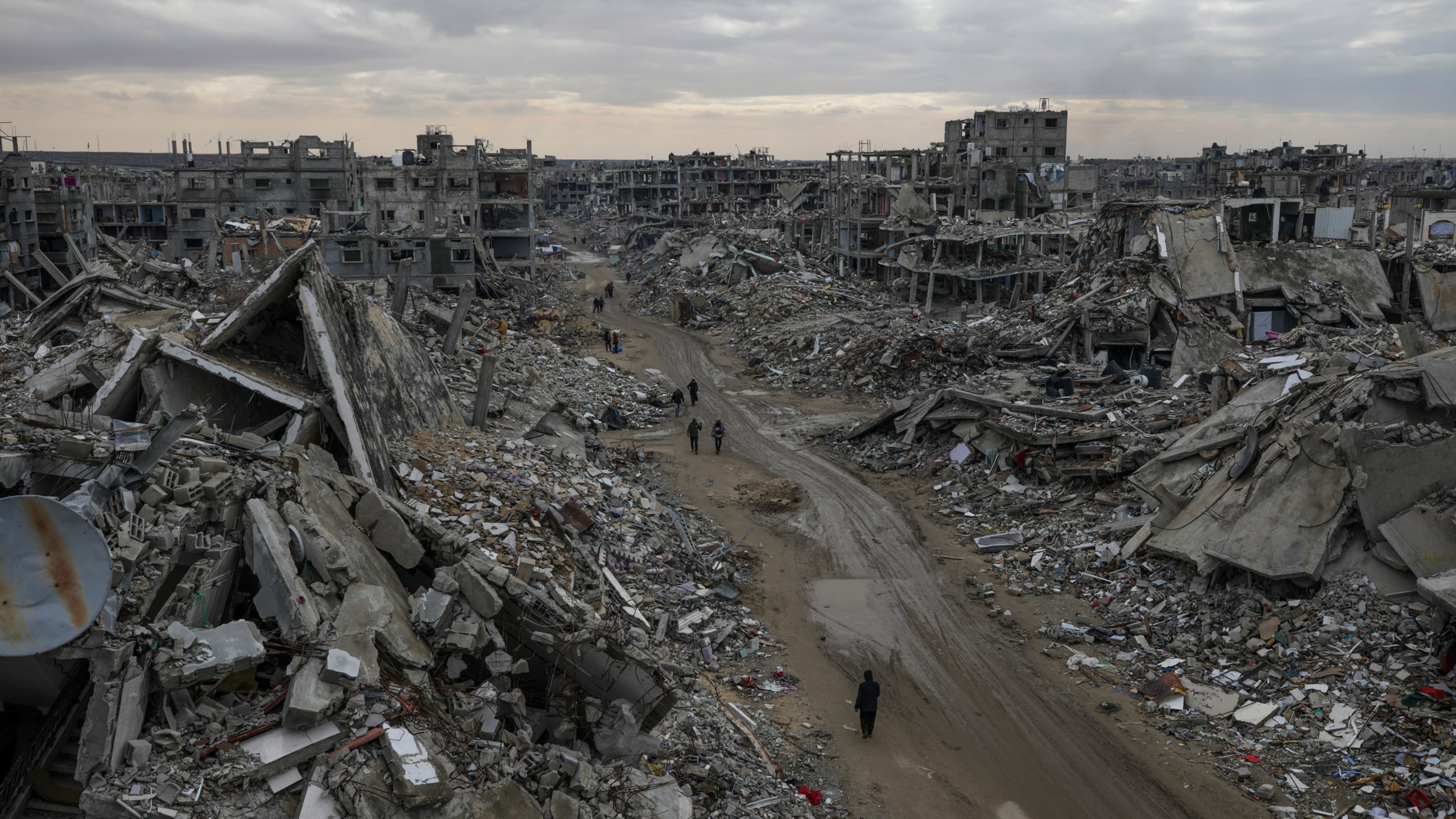 People walk amidst the destruction caused by the Israeli air and ground offensive in Rafah, southern Gaza Strip, Monday, Feb. 24, 2025. (AP Photo/Jehad Alshrafi)