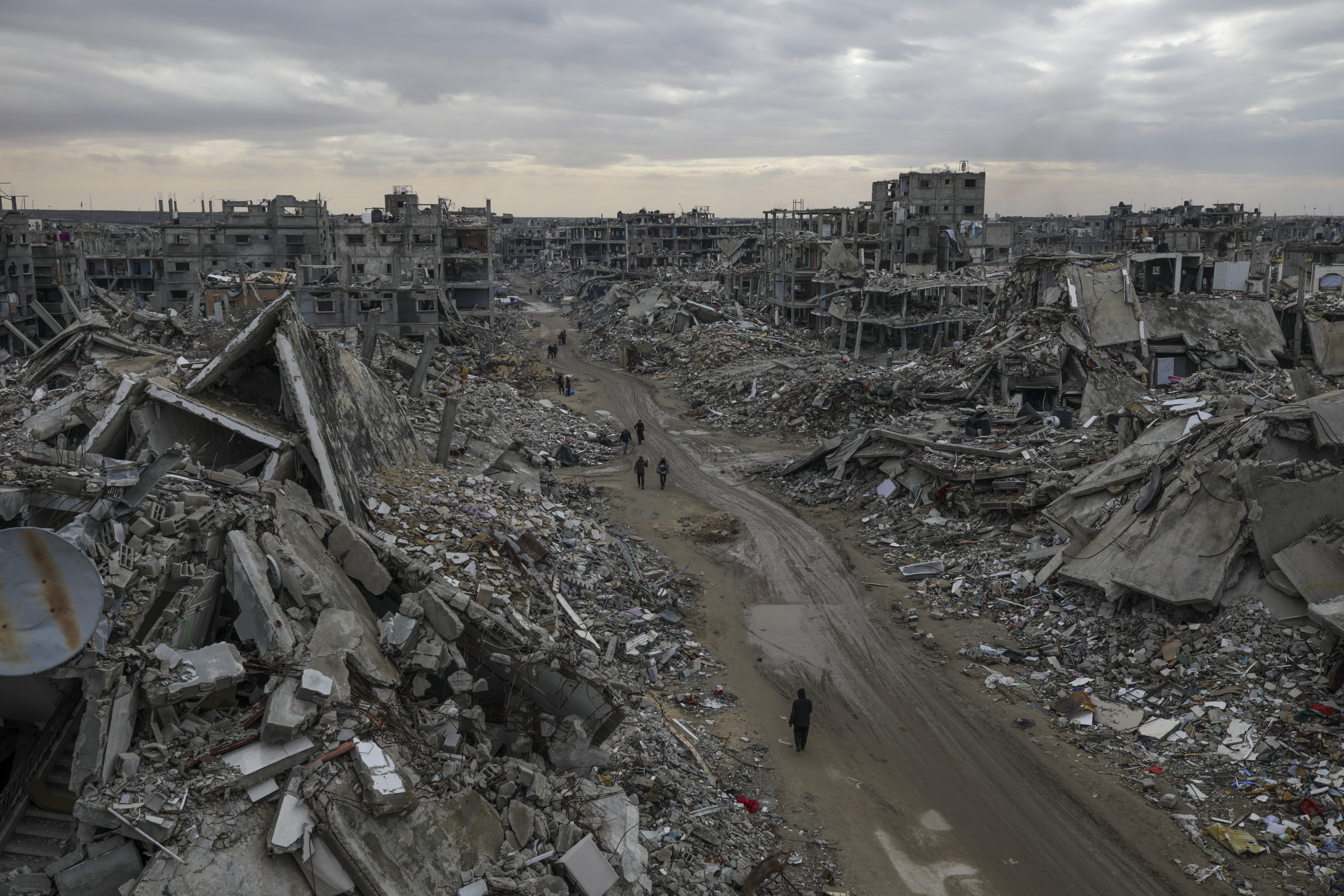 People walk amidst the destruction caused by the Israeli air and ground offensive in Rafah, southern Gaza Strip, Monday, Feb. 24, 2025. (AP Photo/Jehad Alshrafi)