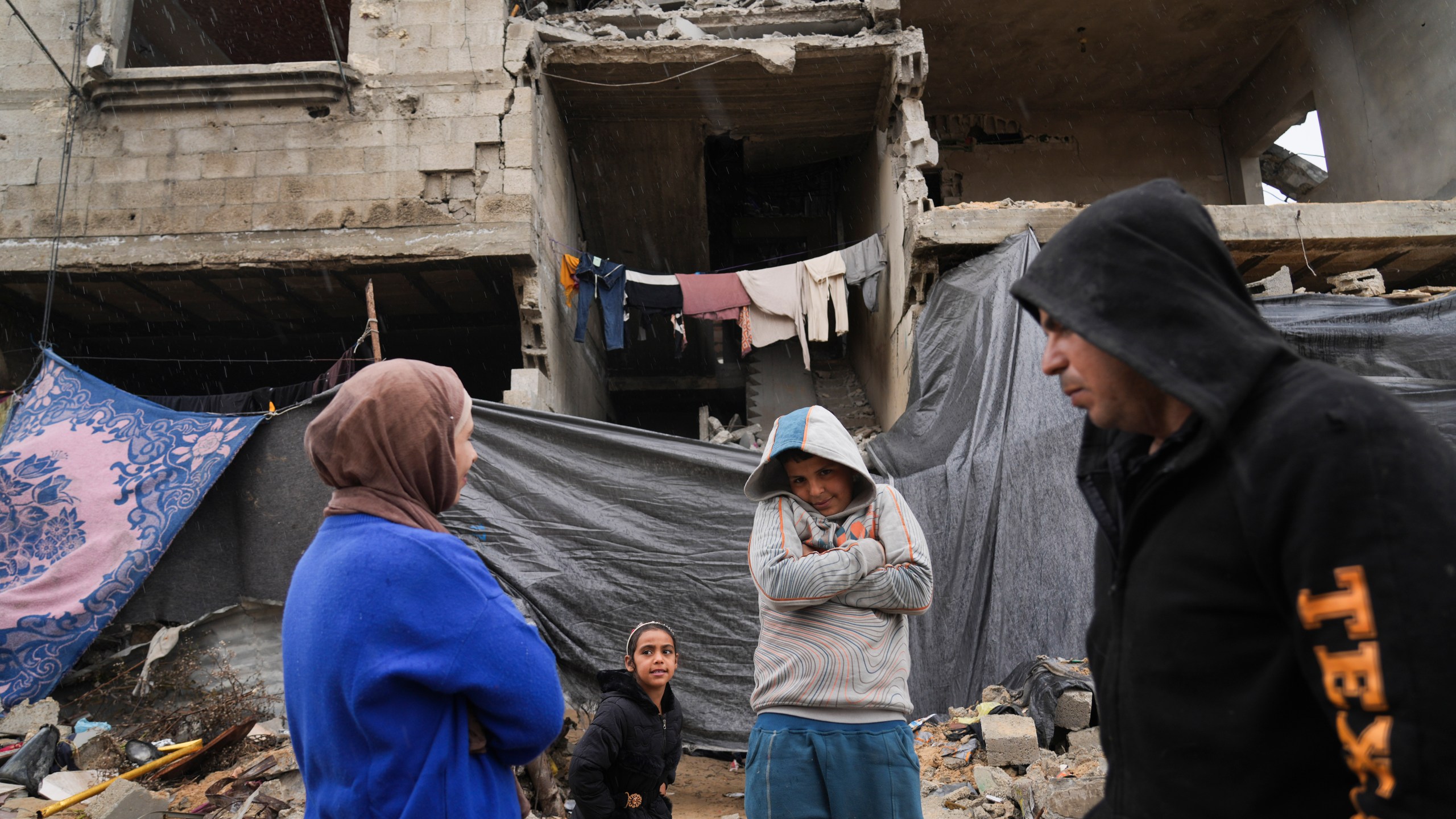 Members of the Tamboura family stand outside their four-story home, which was struck by an Israeli airstrike on Oct. 20, 2023, in Beit Lahiya, northern Gaza Strip, Friday, Feb. 21, 2025. (AP Photo/Abdel Kareem Hana)