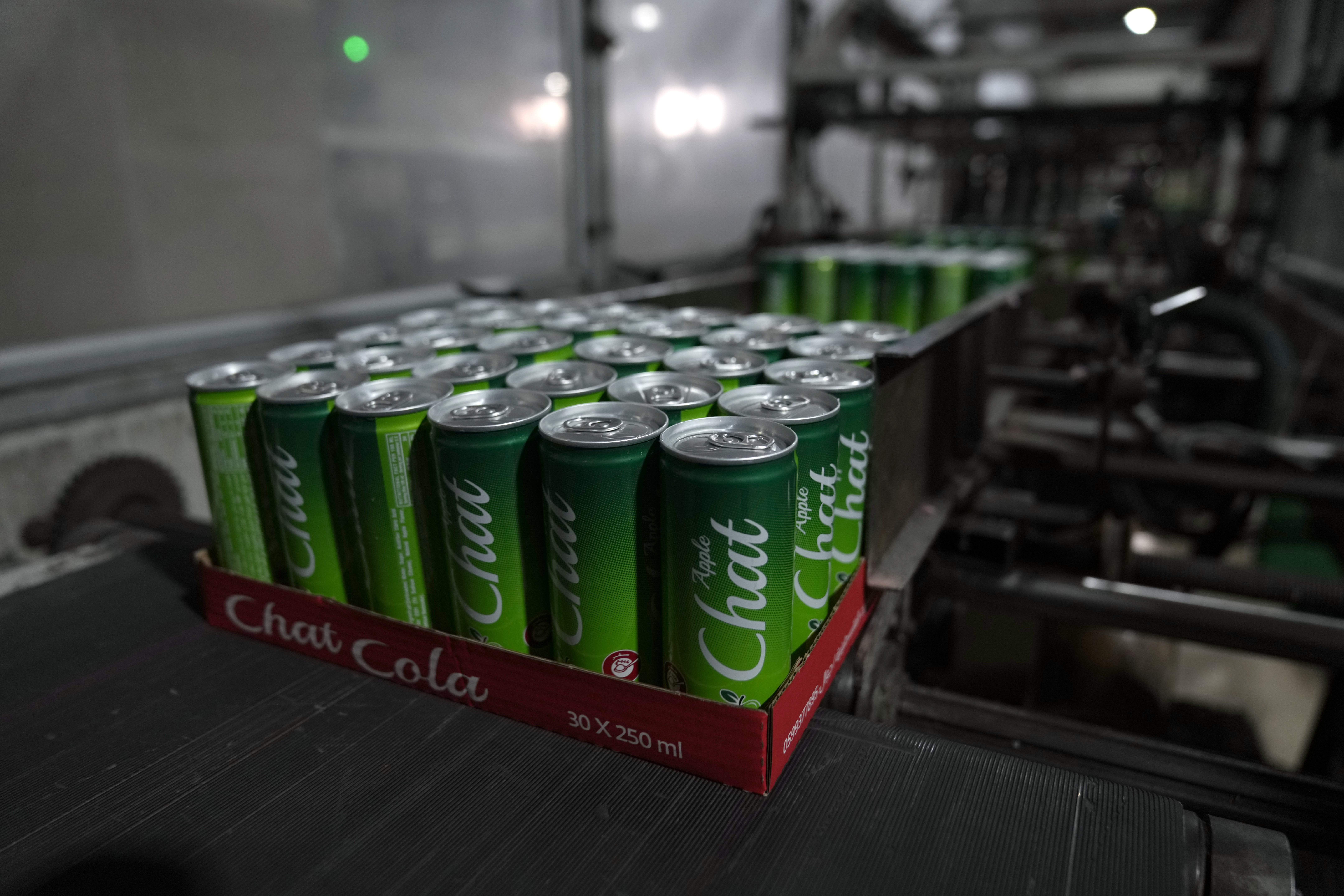 Completed aluminum cans of the Chat Cola Company brand Chat Apple carbonated soft drink move along a production line in the Palestinian company's bottling plant, in the West Bank city of Salfit, Feb. 13, 2025. (AP Photo/Nasser Nasser)