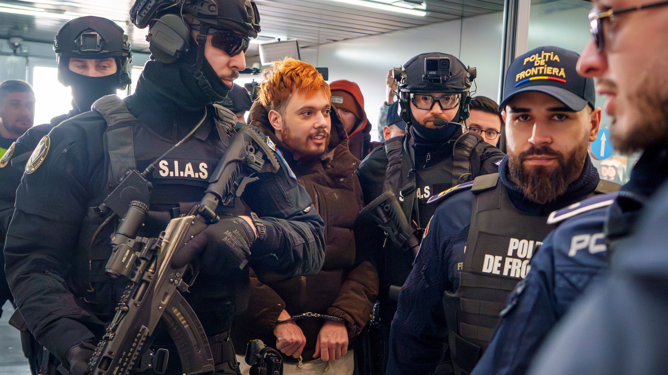 Mohamed Amra, nicknamed ''The Fly", is escorted by armed police officers at the Henri Coanda international airport in Otopeni, Romania, Tuesday, Feb. 25, 2025, before being extradited to France. (AP Photo/Vadim Ghirda)