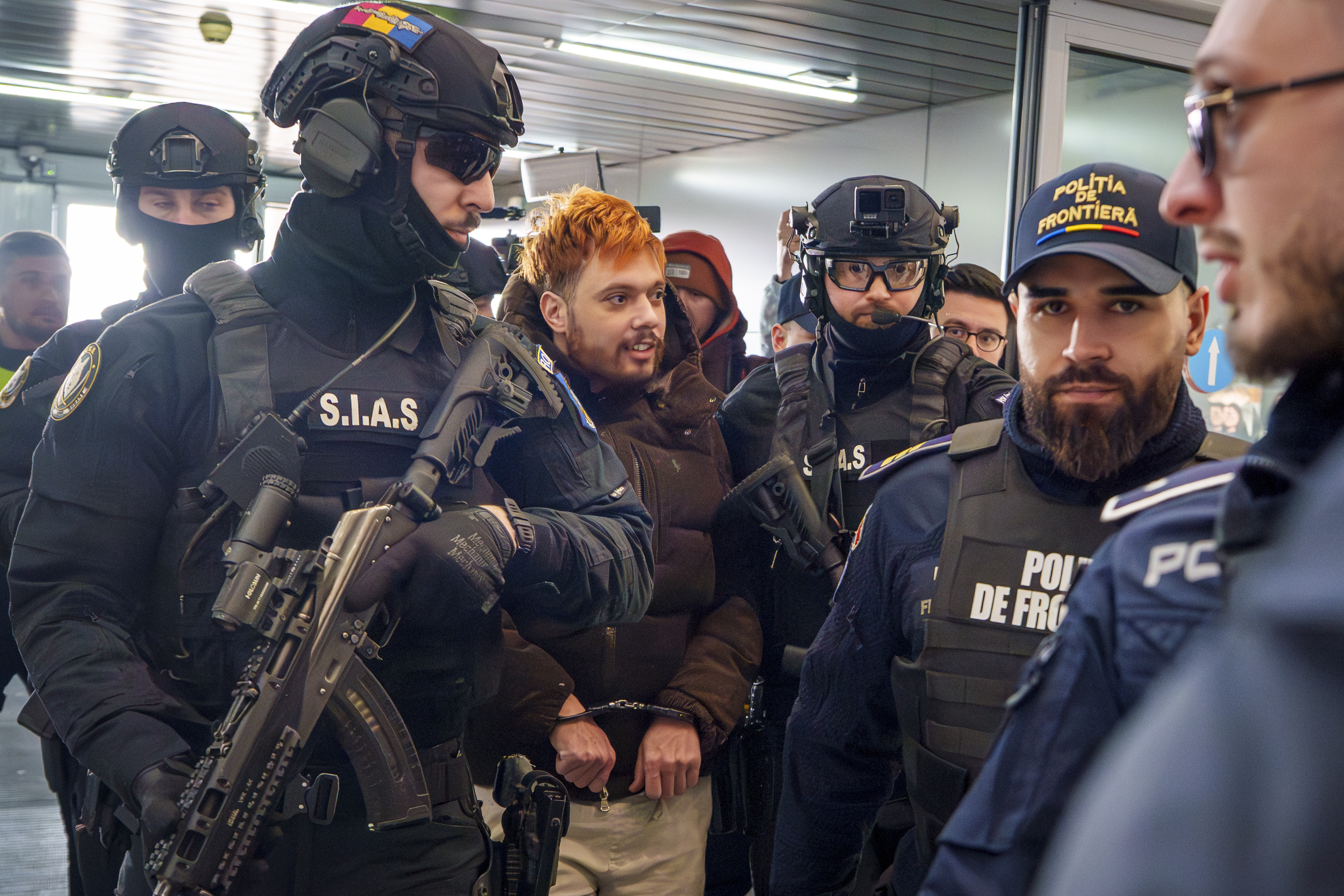 Mohamed Amra, nicknamed ''The Fly", is escorted by armed police officers at the Henri Coanda international airport in Otopeni, Romania, Tuesday, Feb. 25, 2025, before being extradited to France. (AP Photo/Vadim Ghirda)