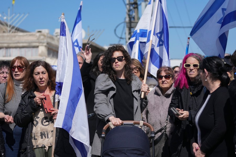 People wave Israeli flags before the funeral of former hostage Oded Lifshitz in Rishon Lezion, central Israel, on Tuesday, Feb. 25, 2025. Lifshitz was abducted by Hamas on Oct. 7, 2023, and his remains were returned from Gaza to Israel last week as part of a ceasefire with Hamas. (AP Photo/Maya Alleruzzo)