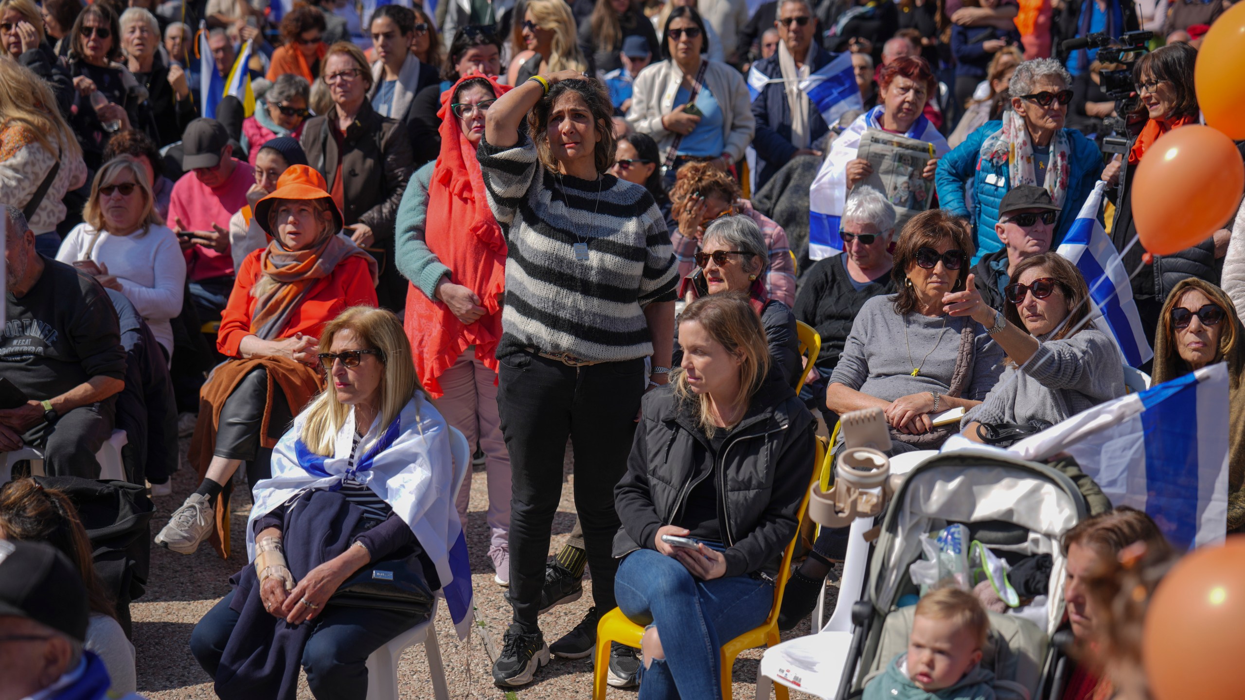 People watch a live broadcast from the funeral of slain hostages Shiri Bibas and her two children, Ariel and Kfir, at a plaza known as the Hostages Square in Tel Aviv, Israel, Wednesday, Feb. 26, 2025. The mother and her two children were abducted by Hamas on Oct. 7, 2023, and their remains were returned from Gaza to Israel last week as part of a ceasefire agreement with Hamas. (AP Photo/Ariel Schalit)