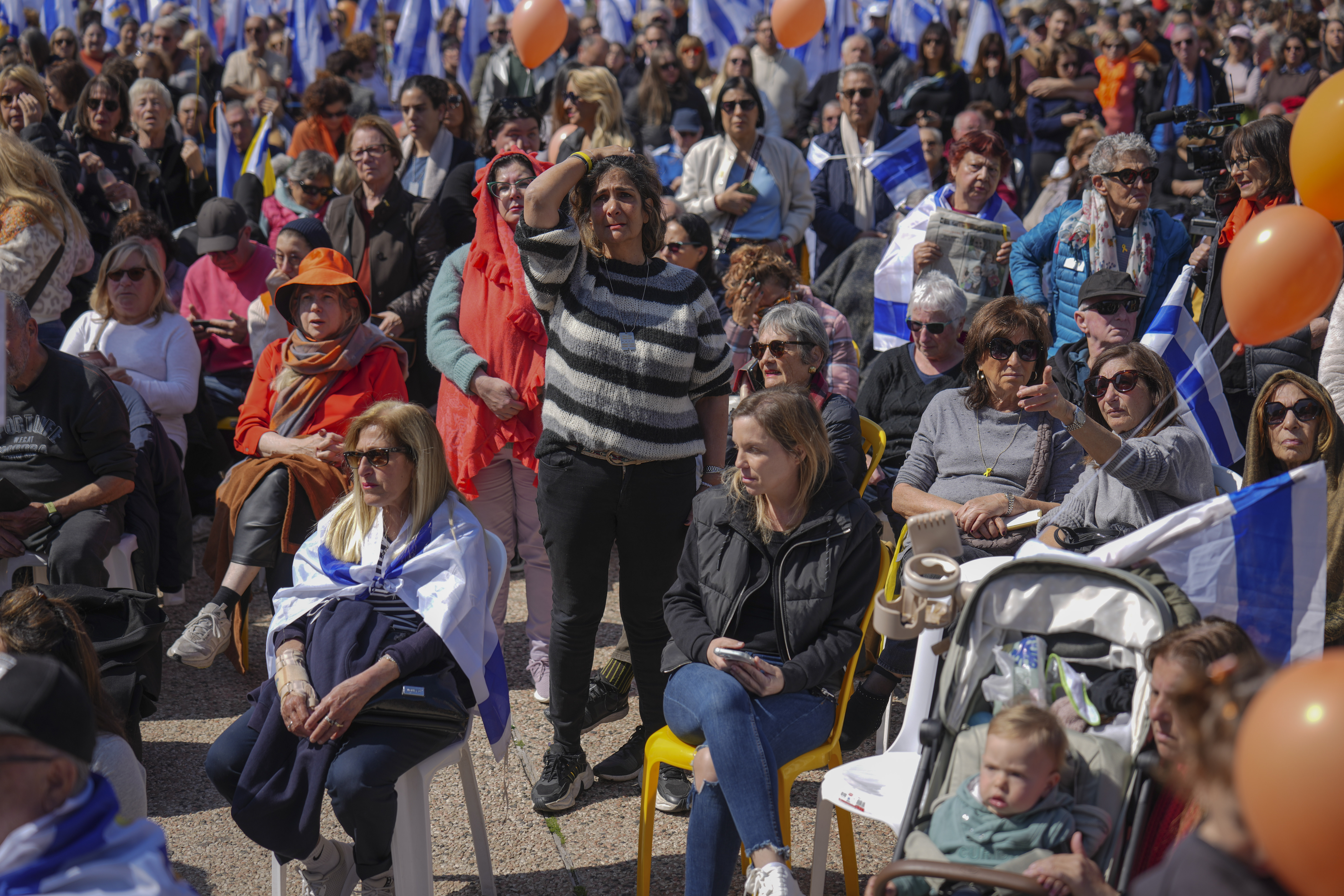 People watch a live broadcast from the funeral of slain hostages Shiri Bibas and her two children, Ariel and Kfir, at a plaza known as the Hostages Square in Tel Aviv, Israel, Wednesday, Feb. 26, 2025. The mother and her two children were abducted by Hamas on Oct. 7, 2023, and their remains were returned from Gaza to Israel last week as part of a ceasefire agreement with Hamas. (AP Photo/Ariel Schalit)