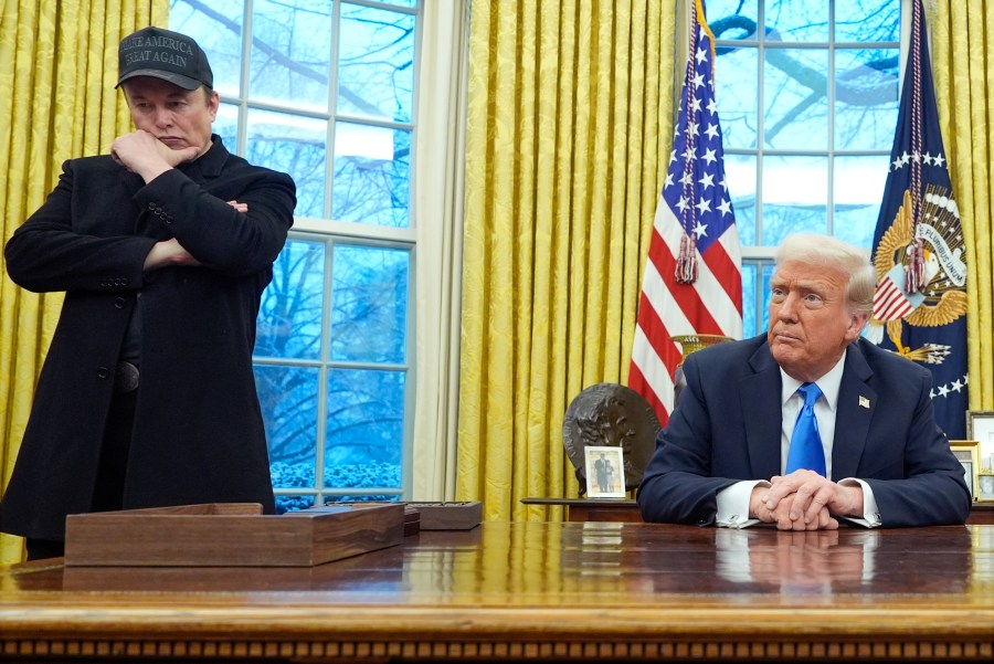 Elon Musk listens as President Donald Trump speaks with reporters in the Oval Office at the White House, Tuesday, Feb. 11, 2025, in Washington. (AP Photo/Alex Brandon)