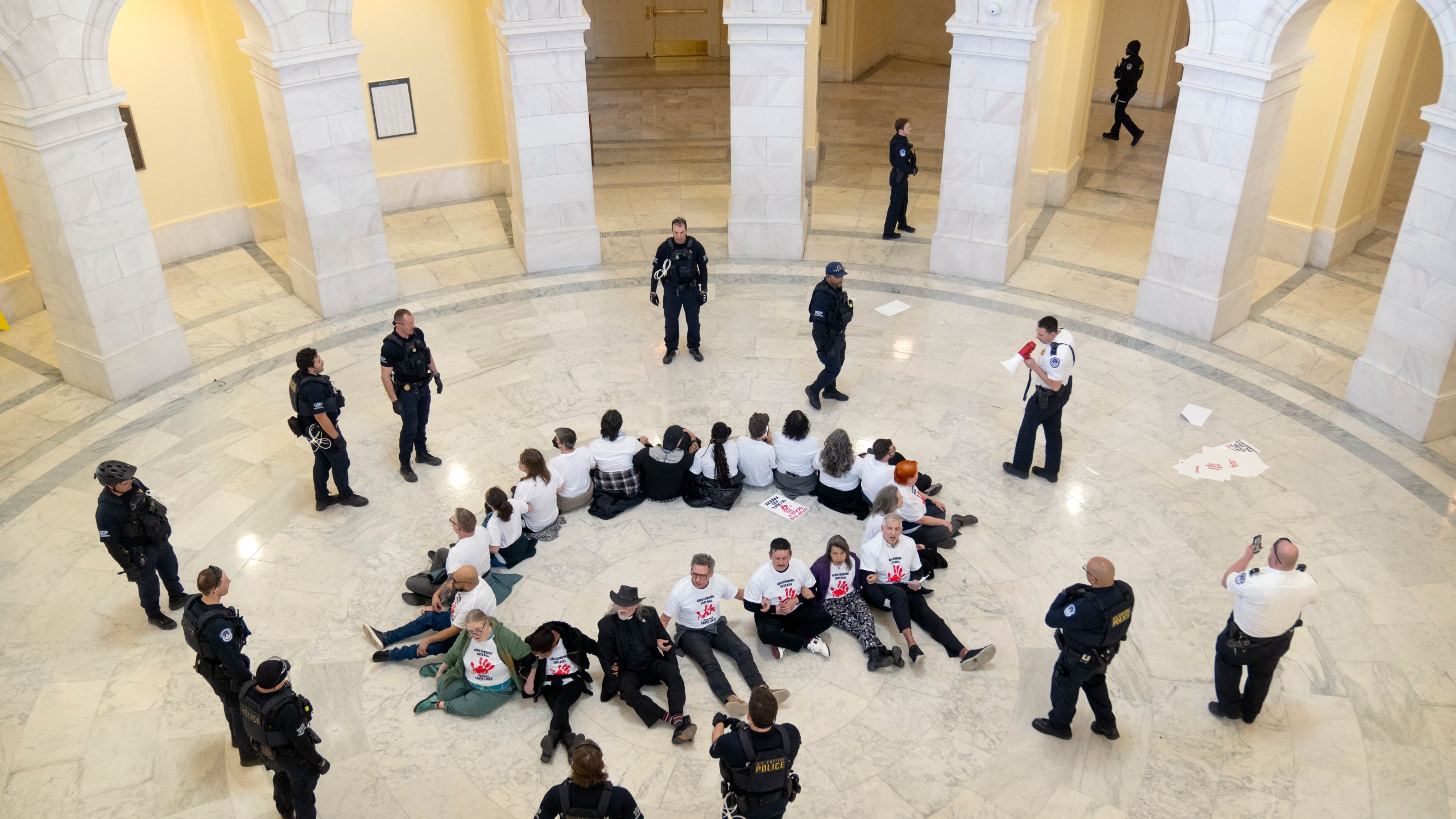 U.S. Capitol Police surround demonstrators as they protest against cuts to American foreign aid spending, including USAID and the PEPFAR program to combat HIV/AIDS, at the Cannon House Office Building on Capitol Hill, Wednesday, Feb. 26, 2025, in Washington. (AP Photo/Mark Schiefelbein)