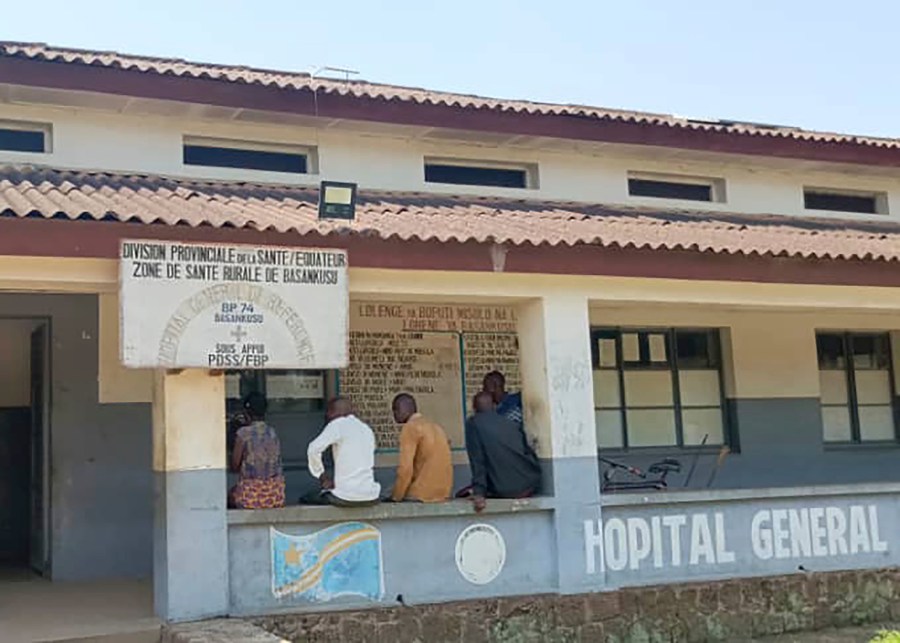 Men sit outside the general hospital in Basankusu, Democratic Republic of the Congo, where some victims of unidentified illnesses are being treated, Thursday, Feb. 27, 2025. (AP Photo/Guy Masele Sanganga)