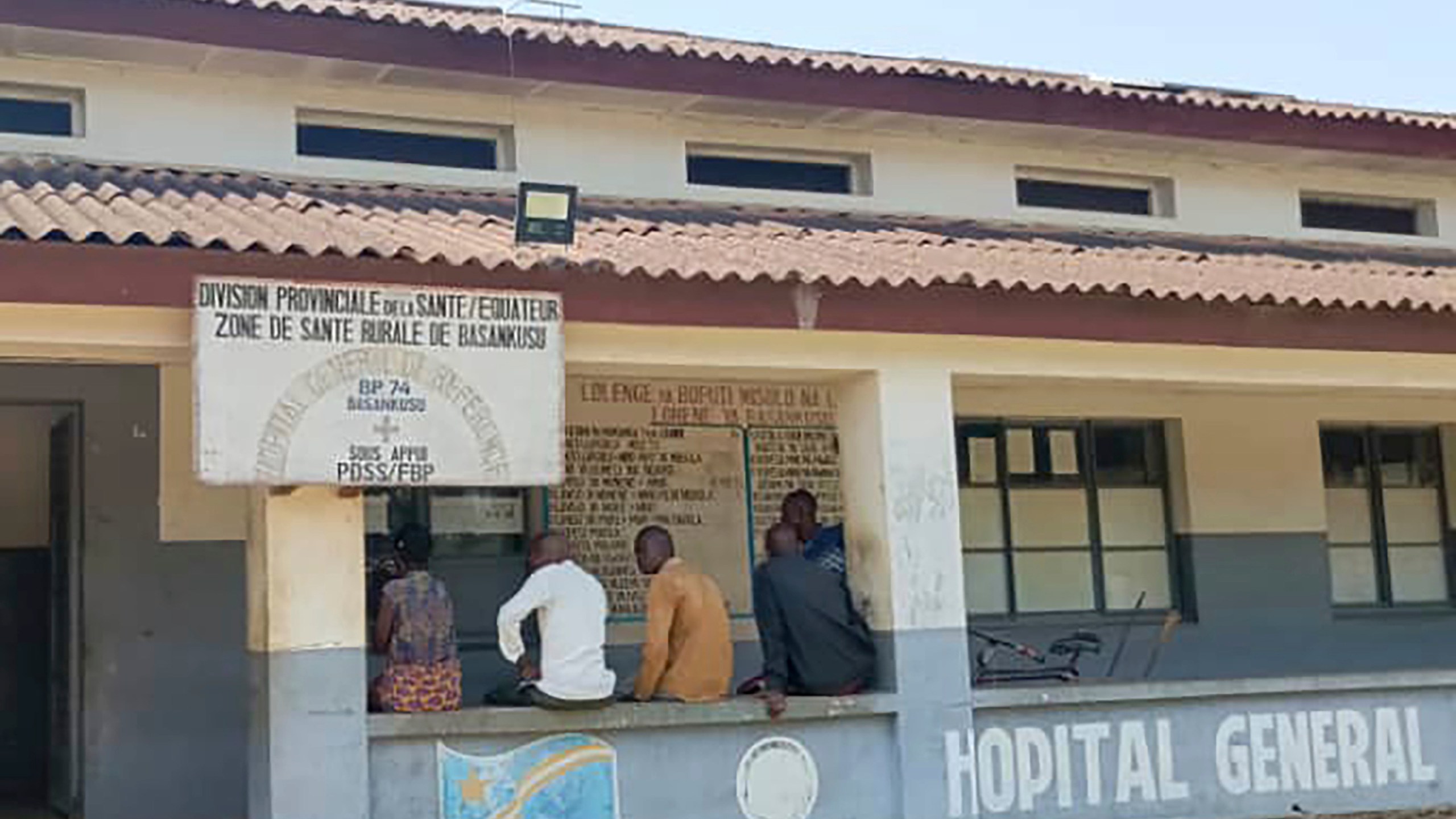 Men sit outside the general hospital in Basankusu, Democratic Republic of the Congo, where some victims of unidentified illnesses are being treated, Thursday, Feb. 27, 2025. (AP Photo/Guy Masele Sanganga)