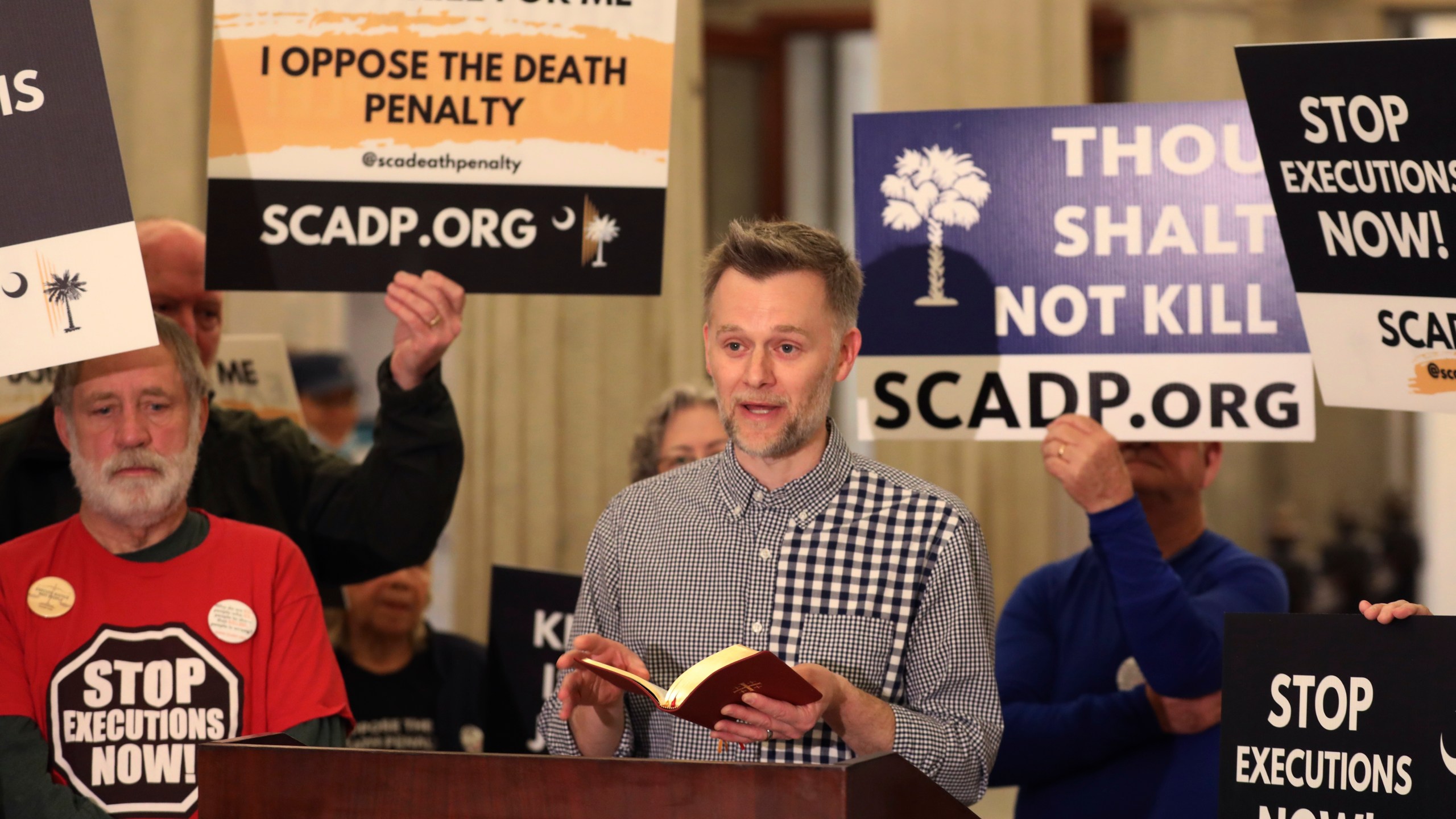 Sam Heath of Equal Justice USA reads scripture before the South Carolinians for Alternatives to the Death Penalty presented a petition to stop the firing squad execution of Brad Sigmon to the South Carolina governor's office on Thursday, March 6, 2025, in Columbia, S.C. (AP Photo/Jeffrey Collins)