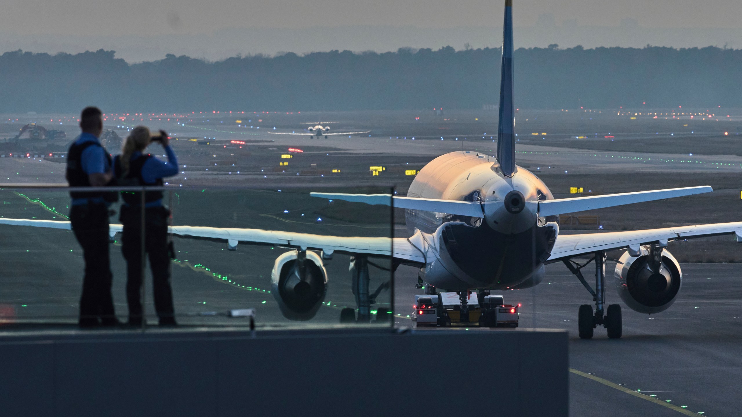 Police officers watch aircrafts take their parking positions at the airport in Frankfurt, Germany, Sunday, March 9, 2025, the evening before a warning strike of all major German airports. (AP Photo/Michael Probst)