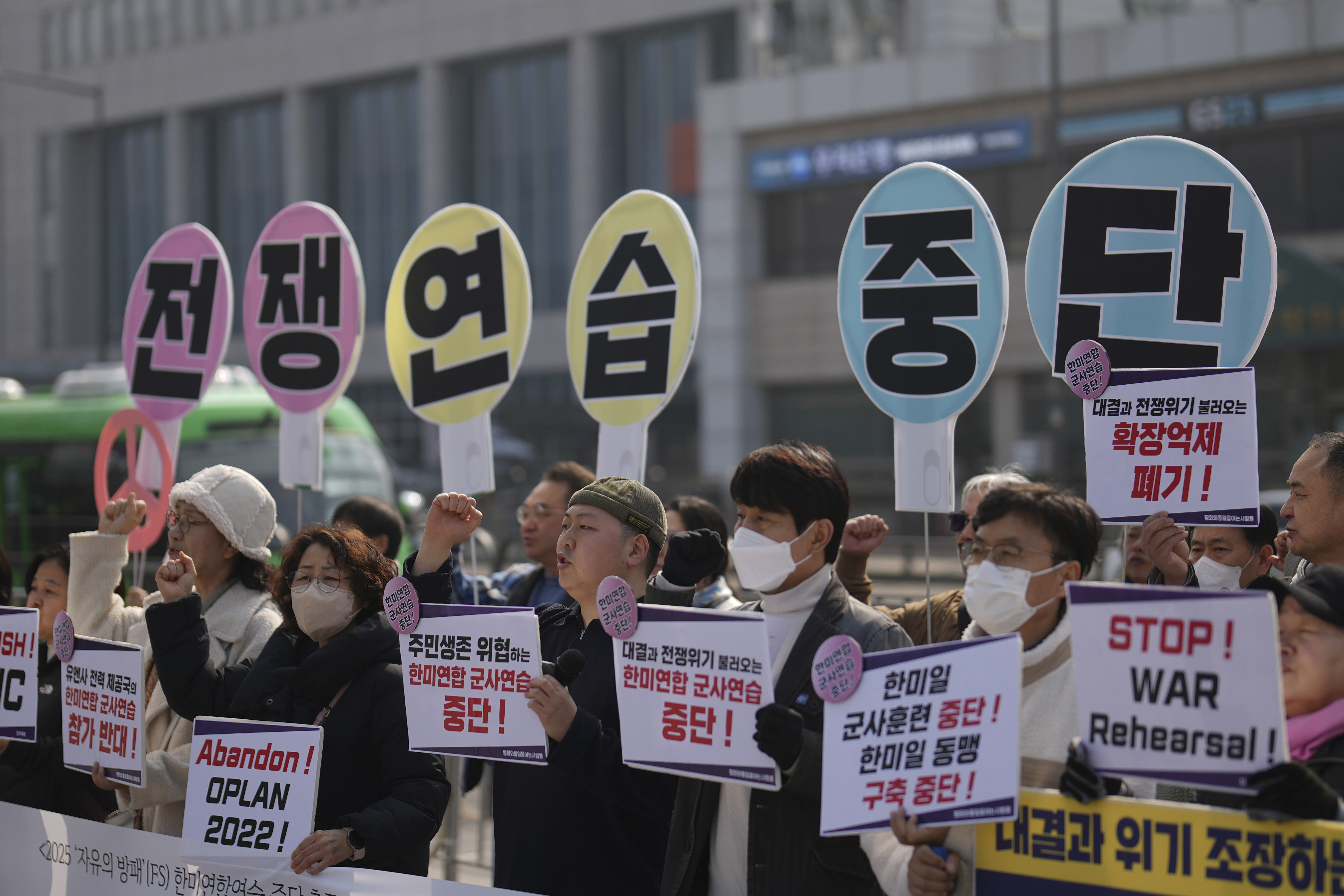 Protesters shout slogans during a press conference demanding to stop the upcoming Freedom Shield military exercise between the U.S. and South Korea, near the Defense Ministry in Seoul, South Korea, Monday, March 10, 2025. The letters read "Stop, War exercise." (AP Photo/Lee Jin-man)