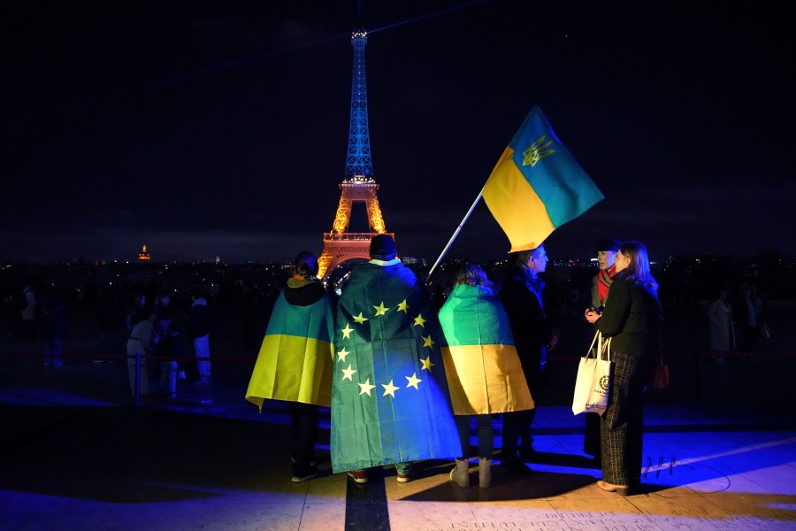 FILE - Ukrainians hold Ukrainian and European flag as the Eiffel Tower is illuminated with the colors of Ukraine to mark the third anniversary of Russia's invasion of the country, in Paris, Monday, Feb. 24, 2025. (AP Photo/Christophe Ena, file)