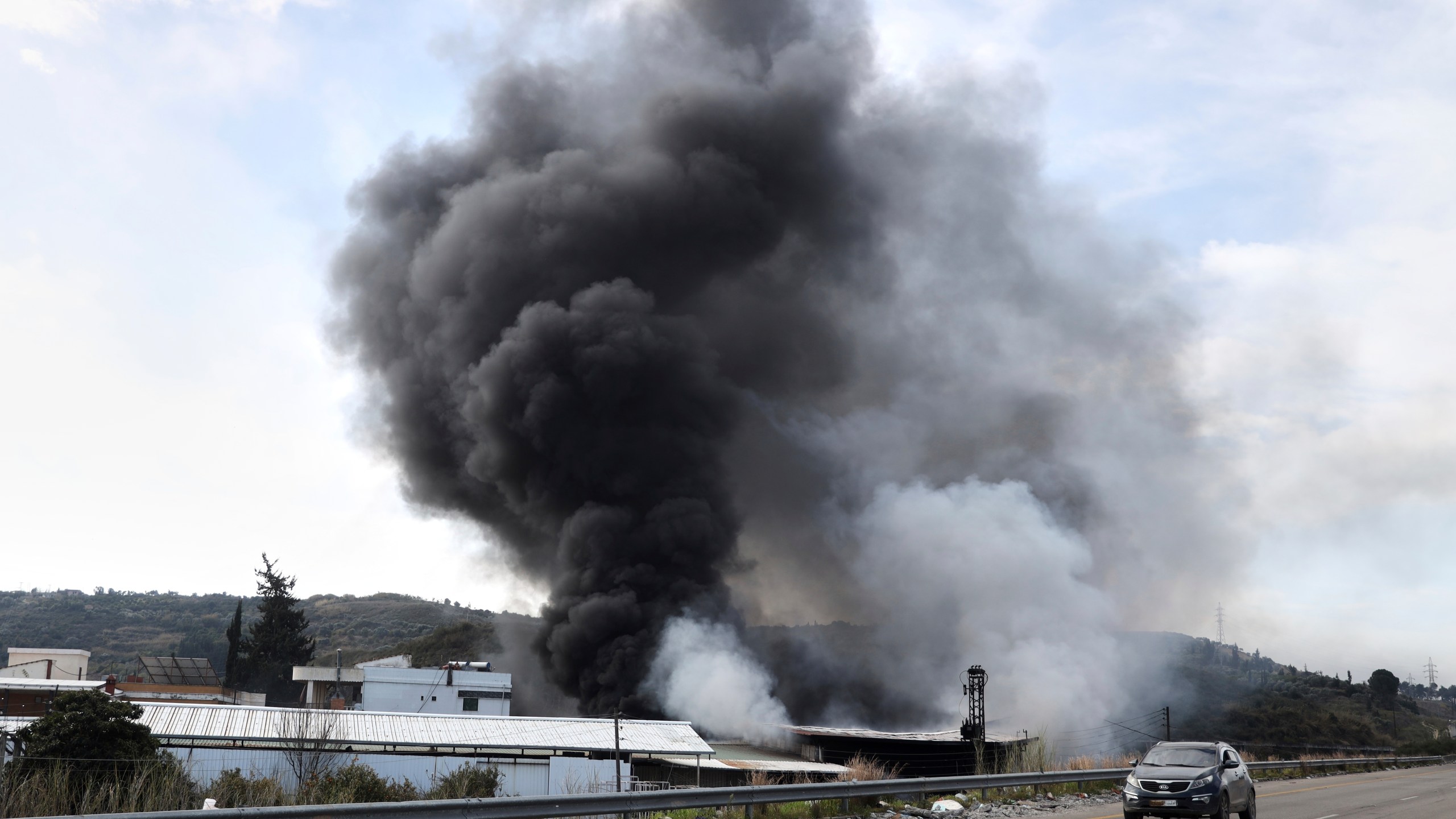 Smoke rises from a factory hit during clashes by Syrian security forces and gunmen loyal to former President Bashar Assad in the outskirts of Latakia, Syria, Friday, March 7, 2025. (AP Photo/Omar Albam)