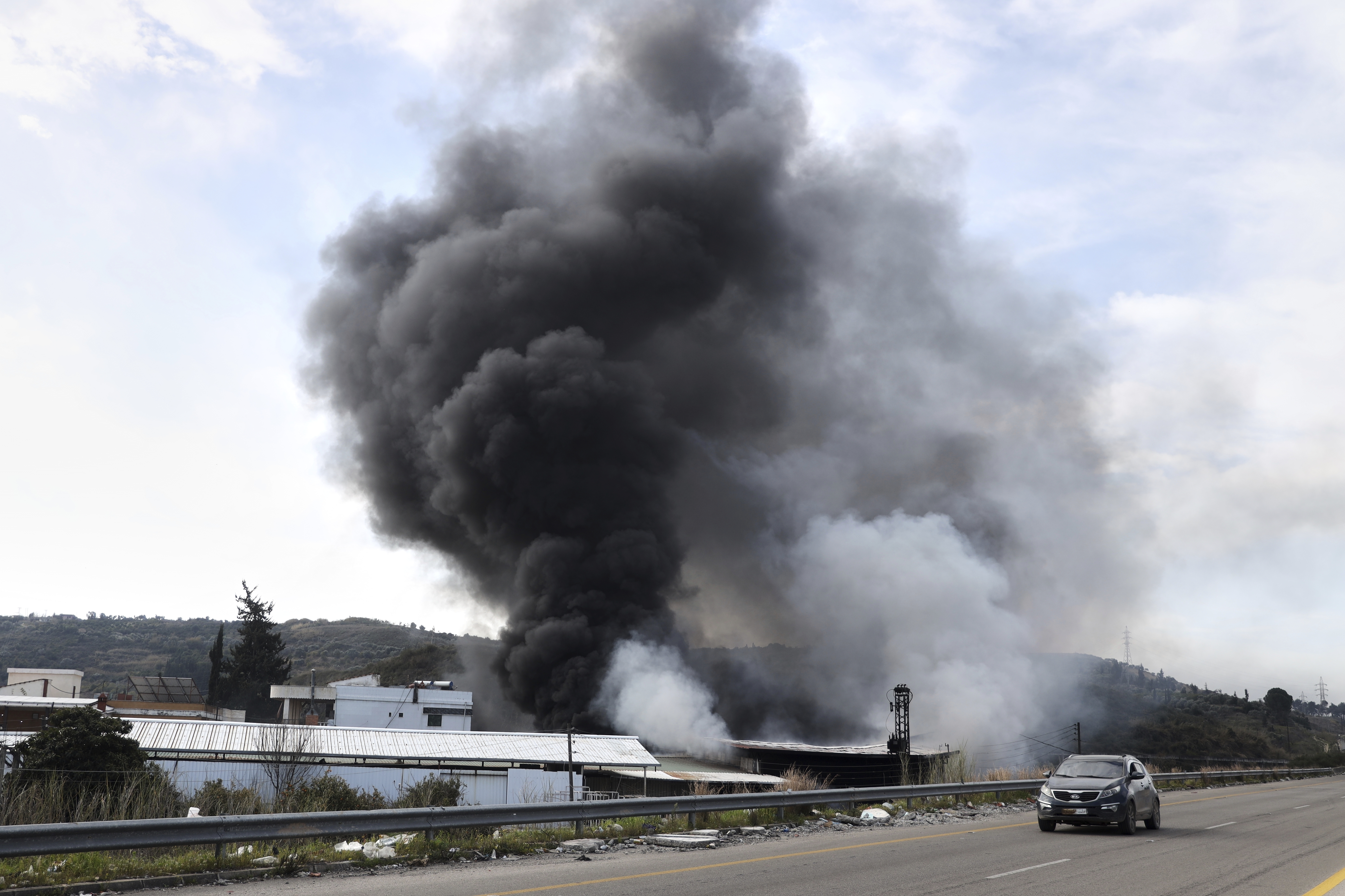 Smoke rises from a factory hit during clashes by Syrian security forces and gunmen loyal to former President Bashar Assad in the outskirts of Latakia, Syria, Friday, March 7, 2025. (AP Photo/Omar Albam)