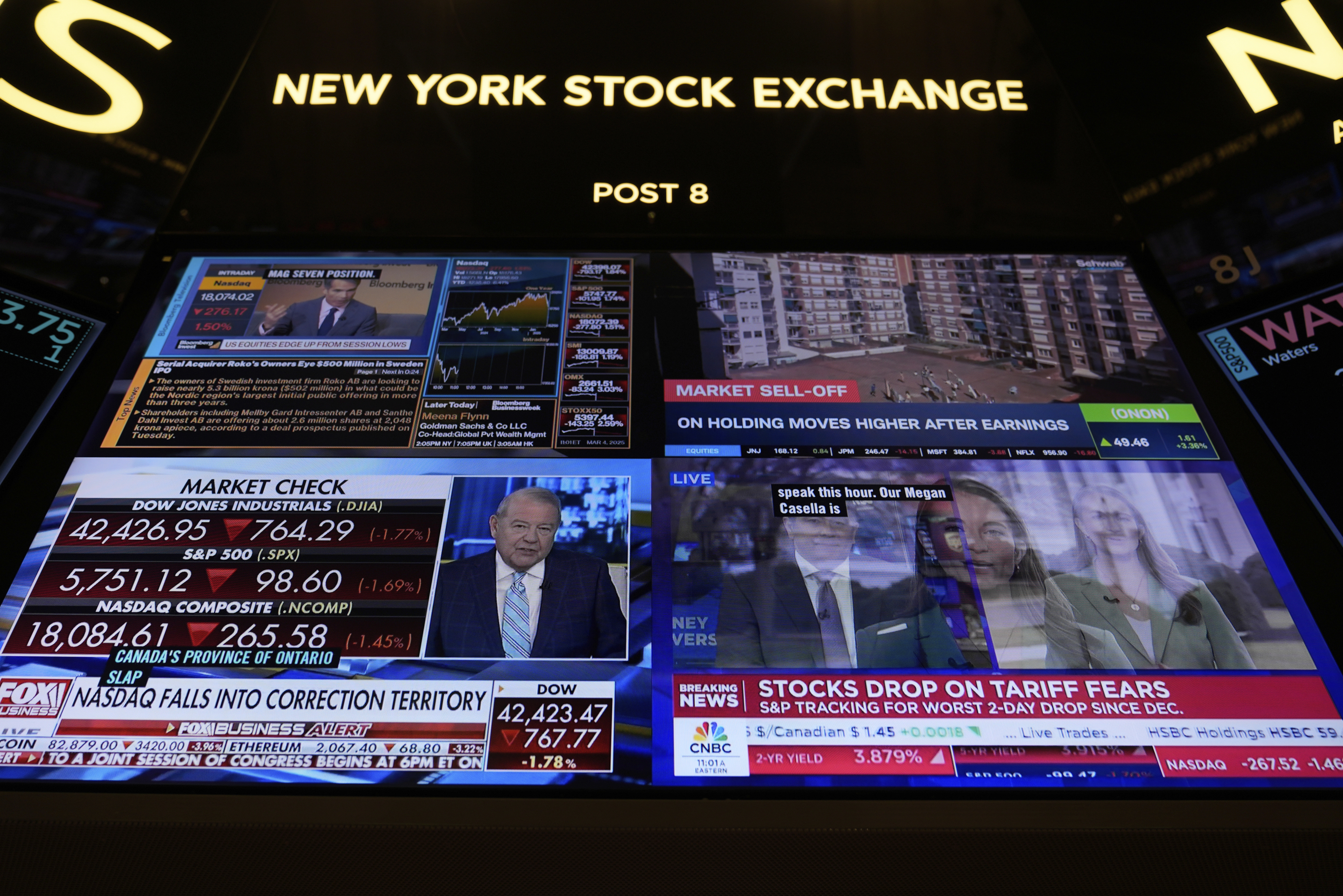 Financial news is displayed as people work on the floor at the New York Stock Exchange in New York, Tuesday, March 4, 2025. (AP Photo/Seth Wenig)