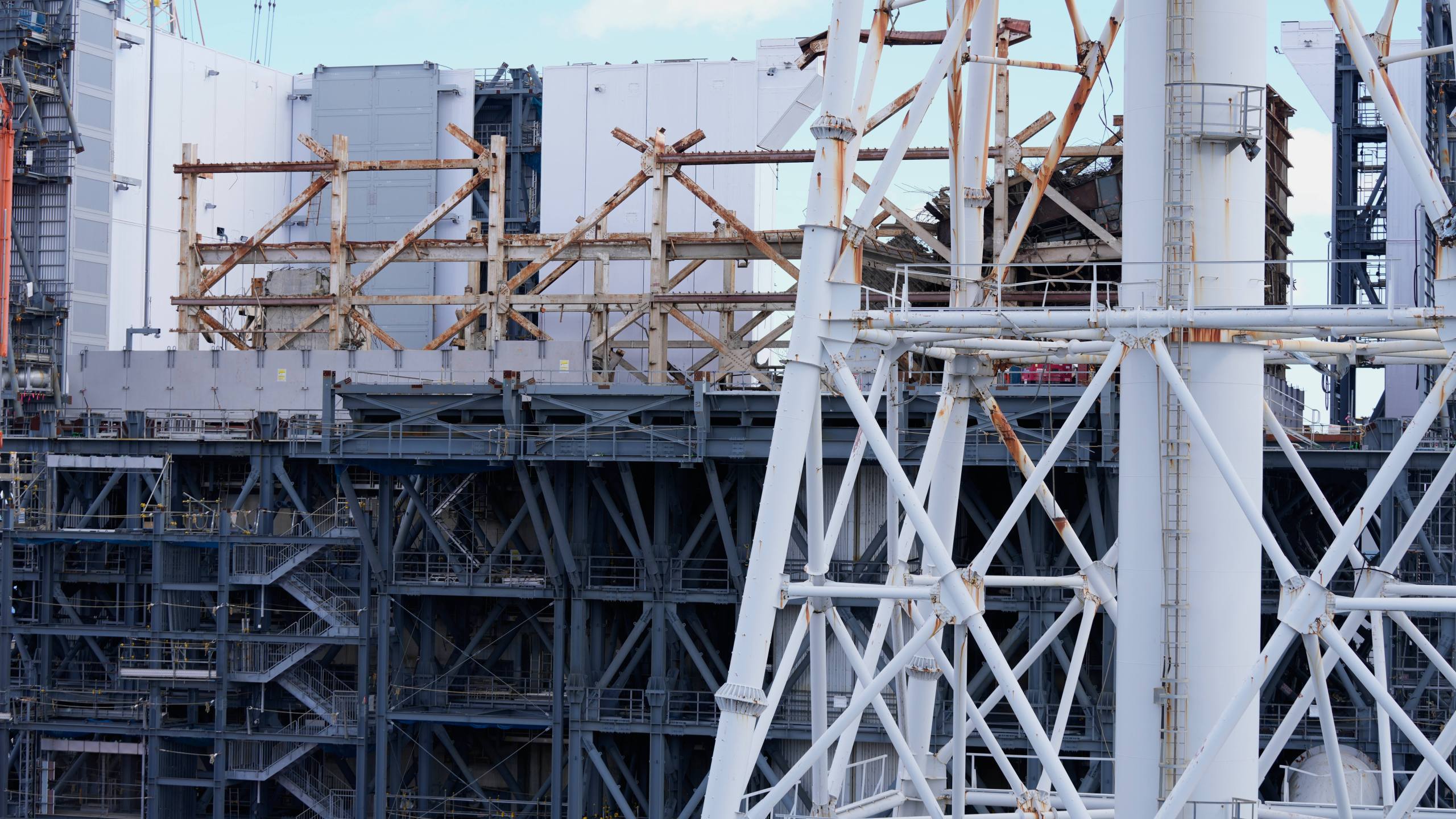 The damaged Unit 1 reactor, back, and the exhaust stack shared by the Unit 1 and 2 reactors are seen at the Fukushima Daiichi nuclear power plant, run by Tokyo Electric Power Company Holdings (TEPCO), in Okuma town, northeastern Japan, on Monday Feb. 20, 2025. (AP Photo/Eugene Hoshiko)