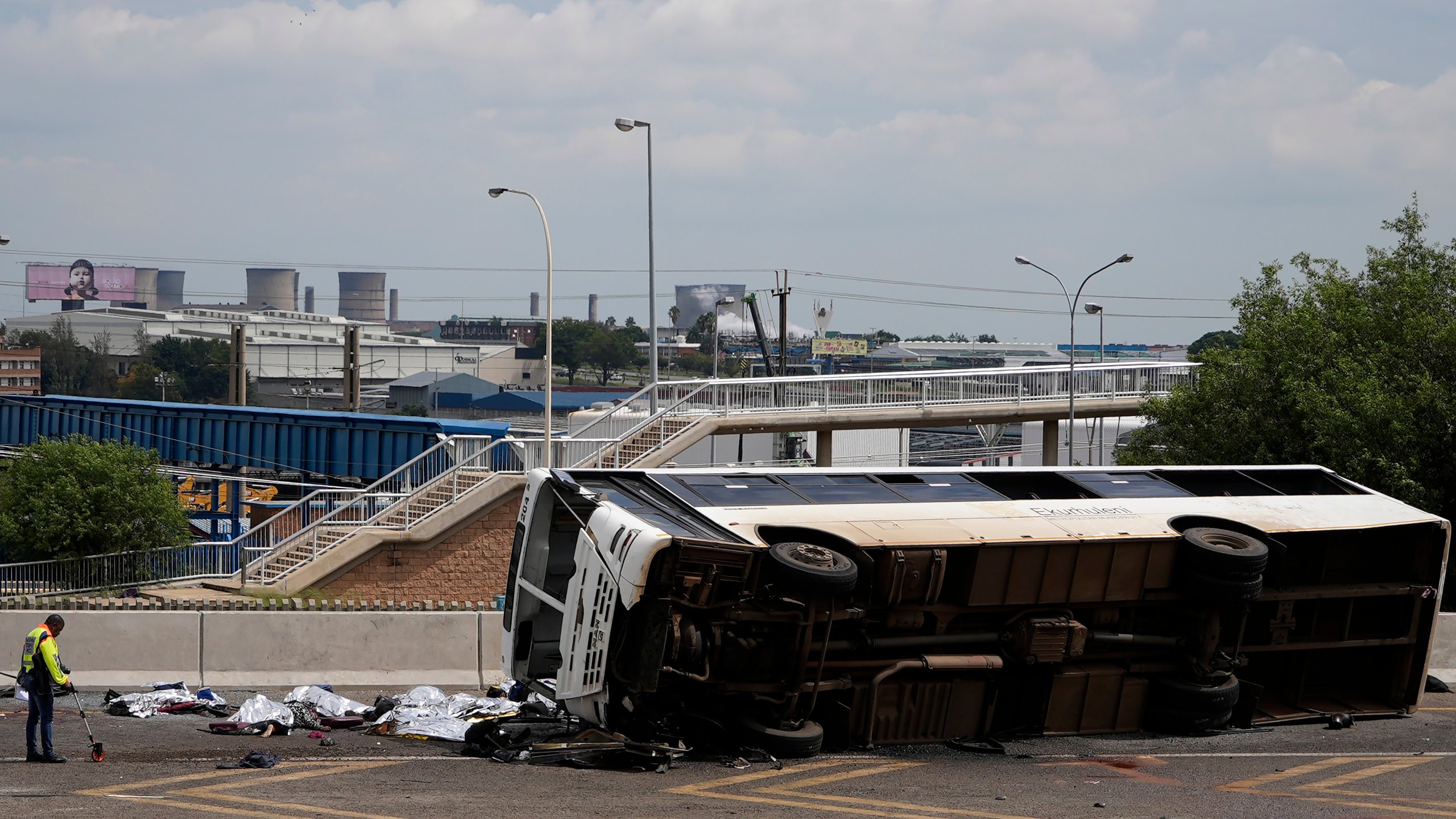 A forensic officer investigate a bus that overturned on a highway in Johannesburg, South Africa, Tuesday, March 11, 2025, killing multiple people and injuring some. (AP Photo/Alfonso Nqunjana)