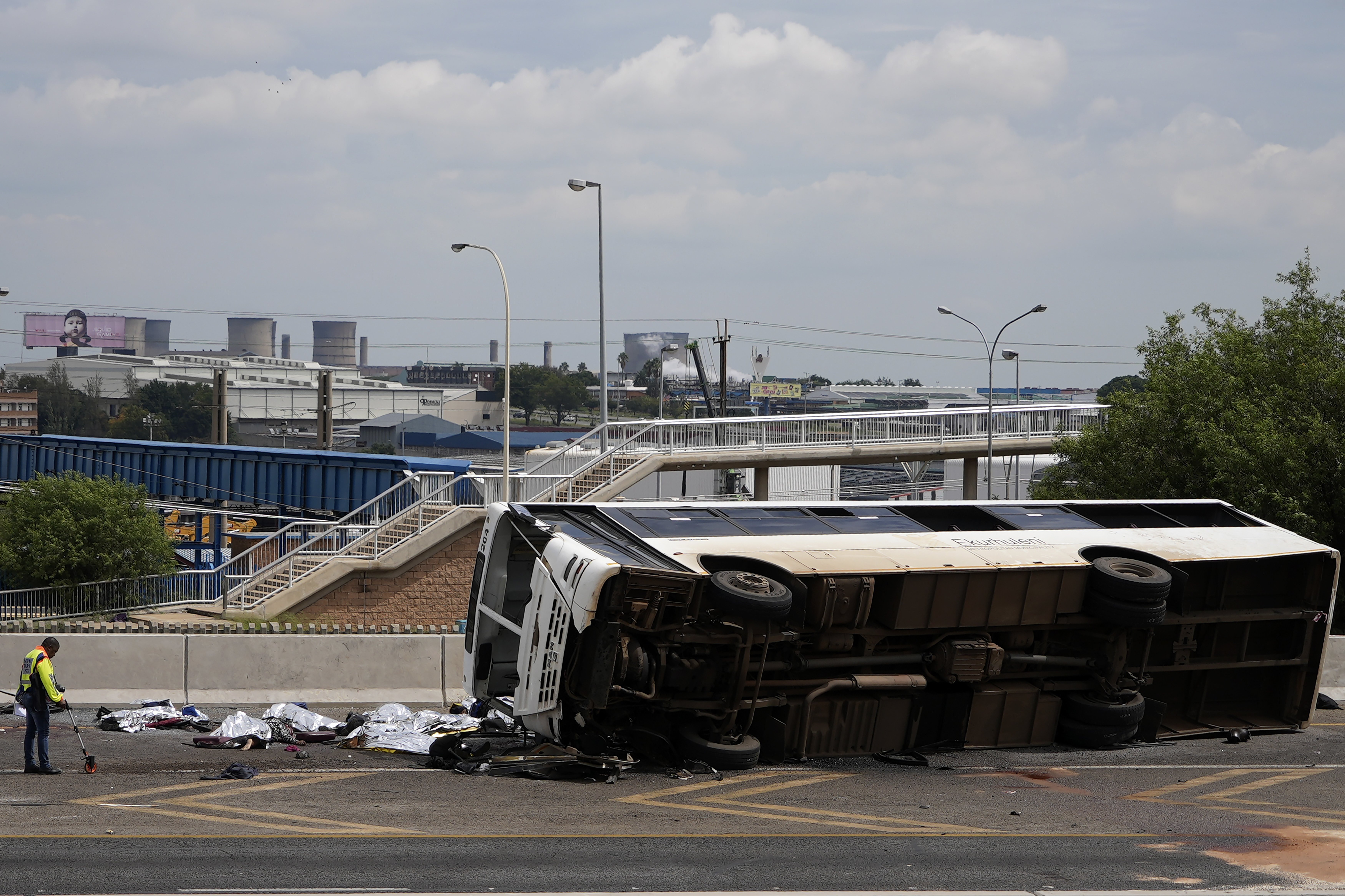 A forensic officer investigate a bus that overturned on a highway in Johannesburg, South Africa, Tuesday, March 11, 2025, killing multiple people and injuring some. (AP Photo/Alfonso Nqunjana)